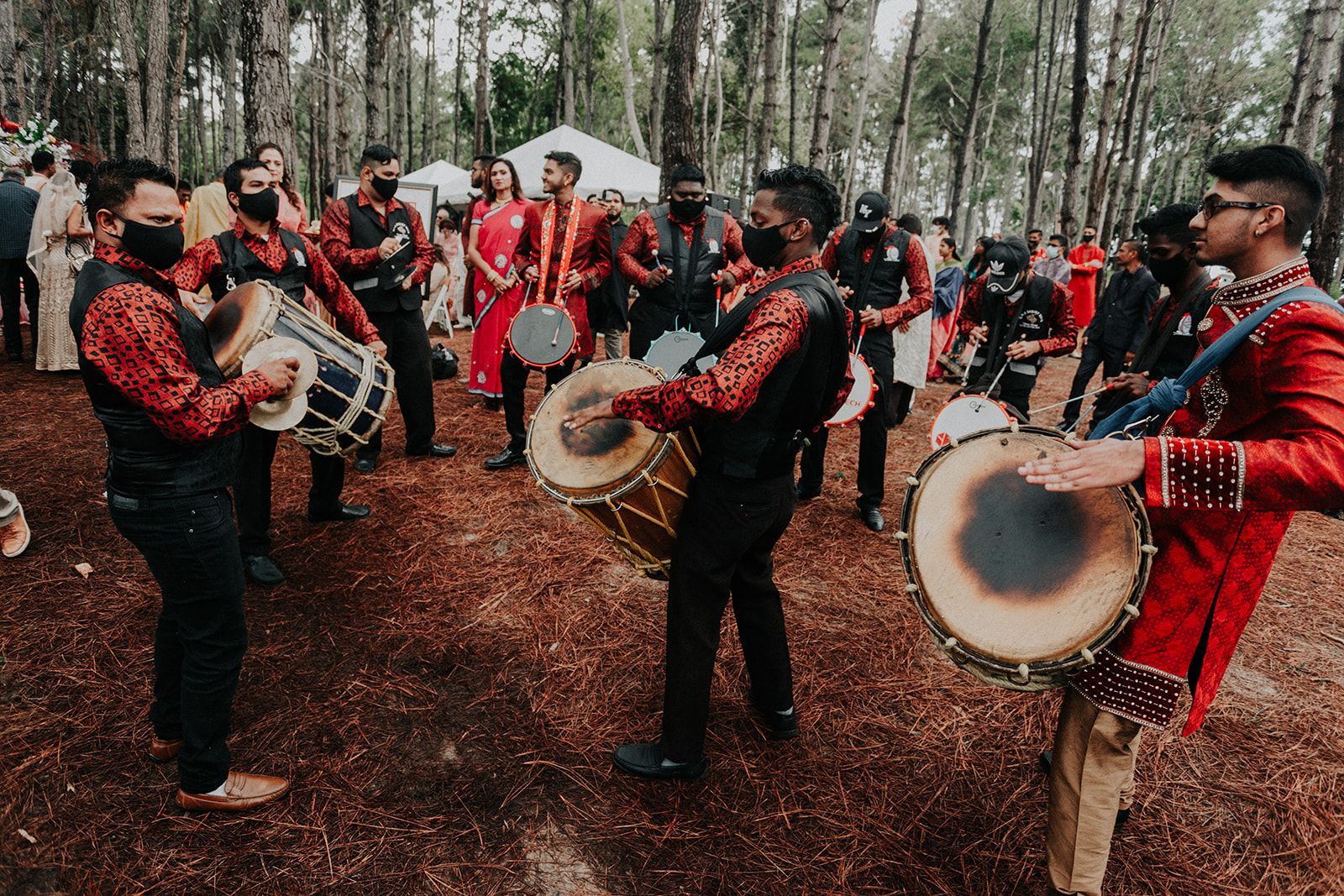 A group of men are playing drums in a forest.