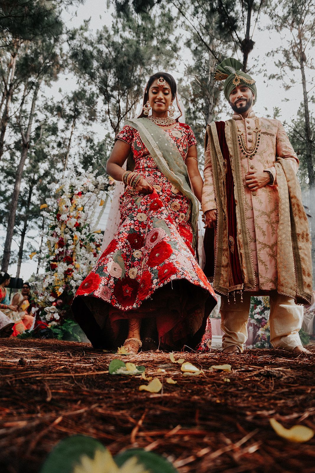 A bride and groom are standing next to each other in a forest.