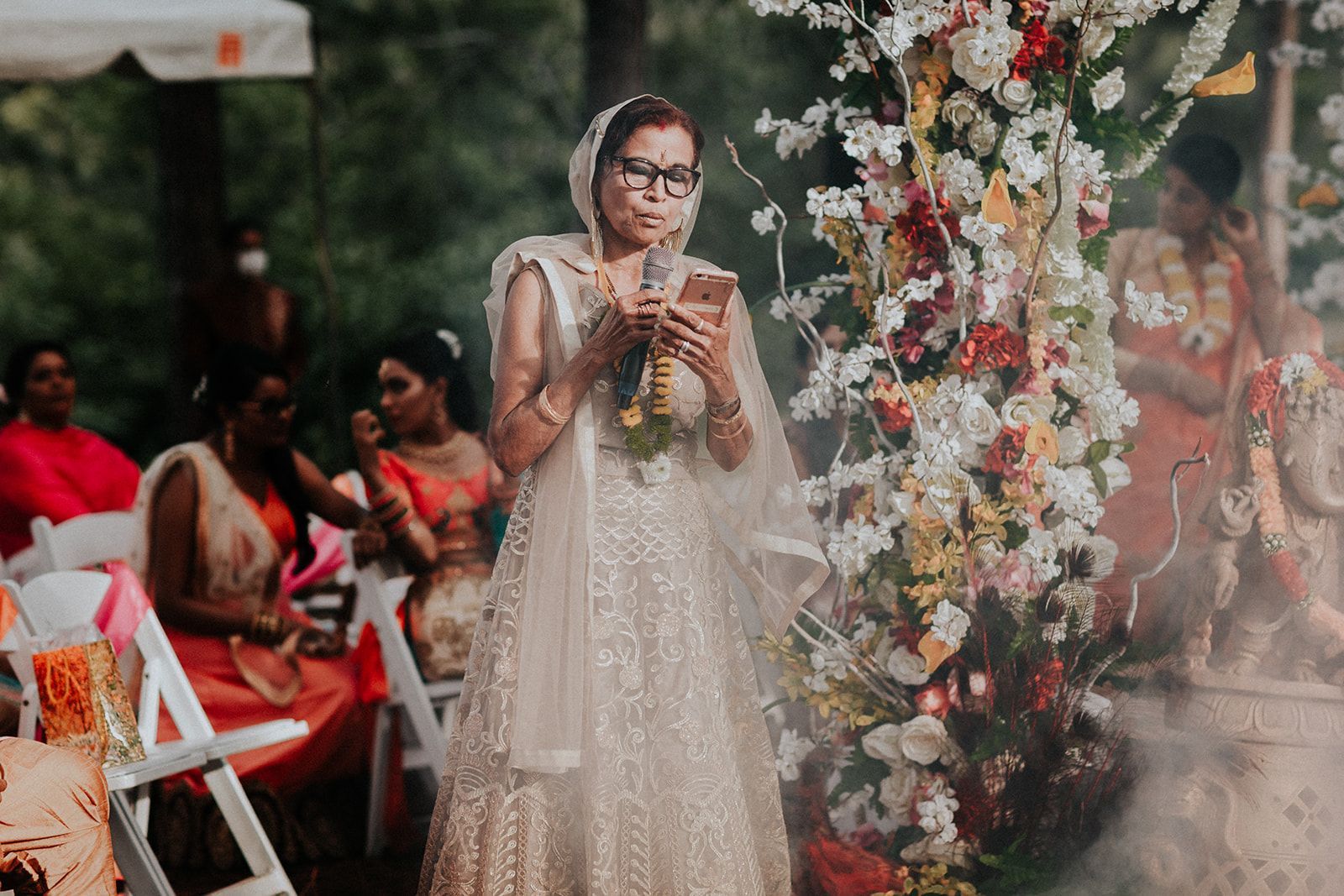 A woman in a wedding dress is holding a microphone and looking at her phone.