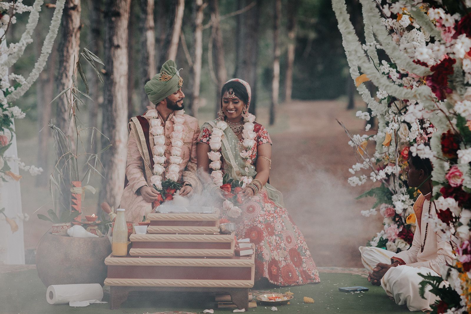 A bride and groom are sitting under a tree at their wedding ceremony.