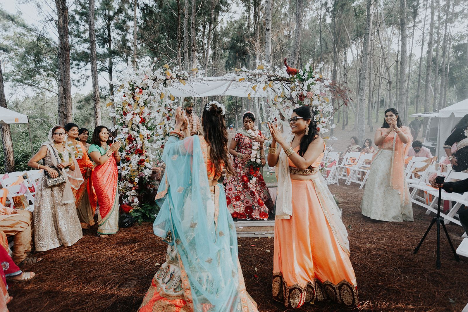A group of women are dancing in the woods at a wedding.