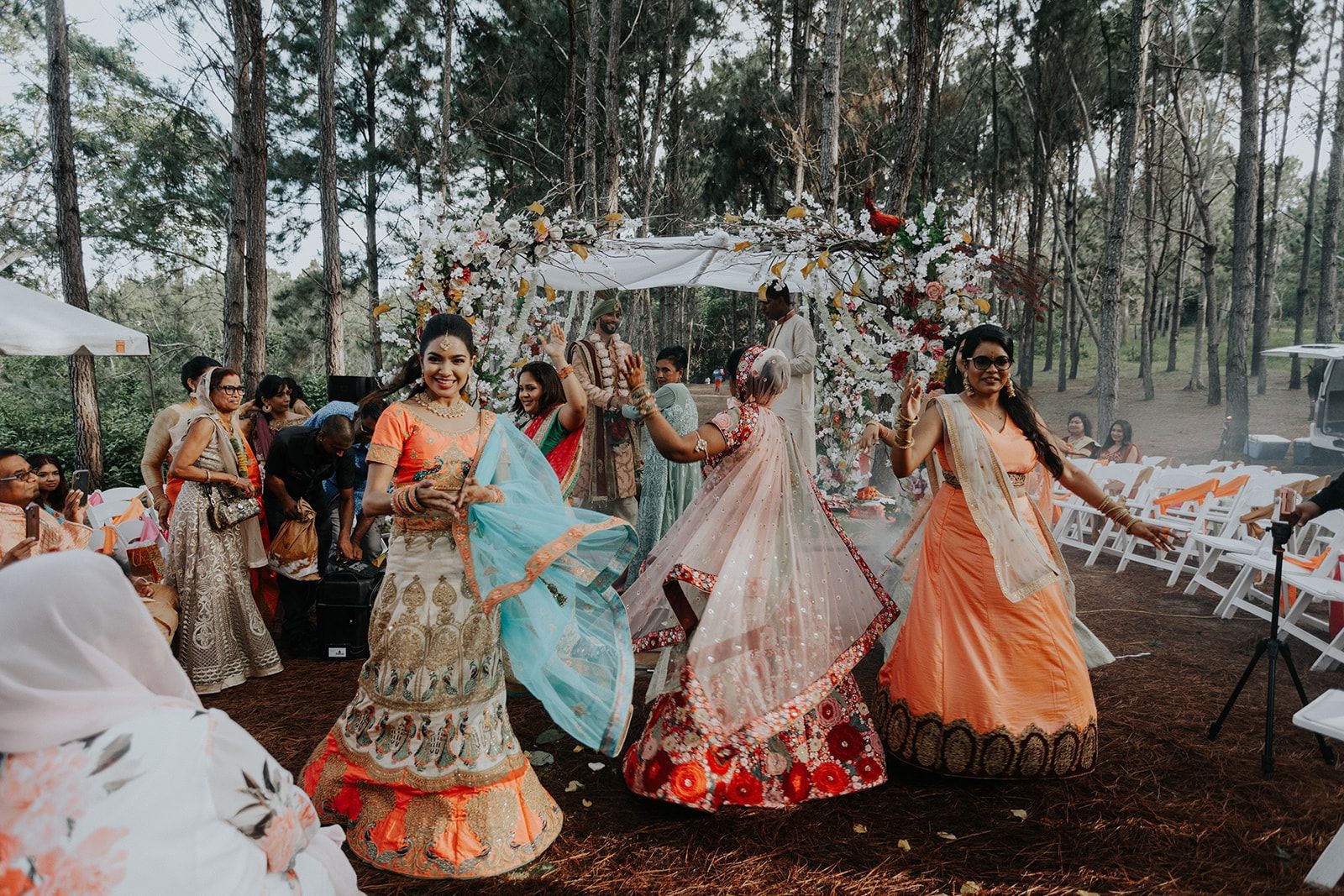 A group of women are dancing in the woods at a wedding.