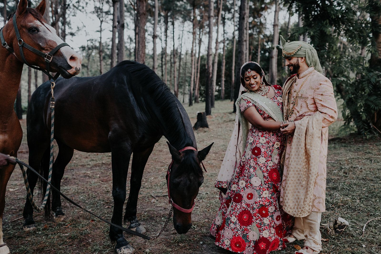 A bride and groom are standing next to a horse in the woods.
