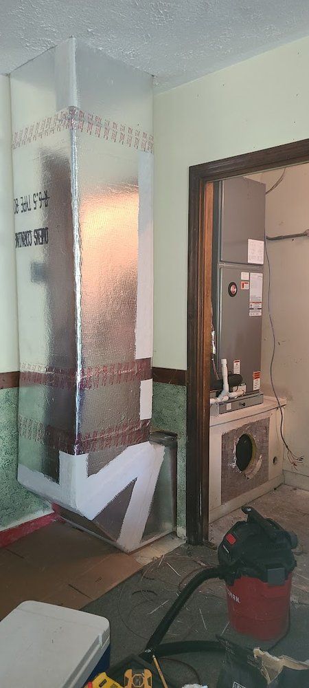 A room with a vacuum cleaner in it and a painting on the wall.