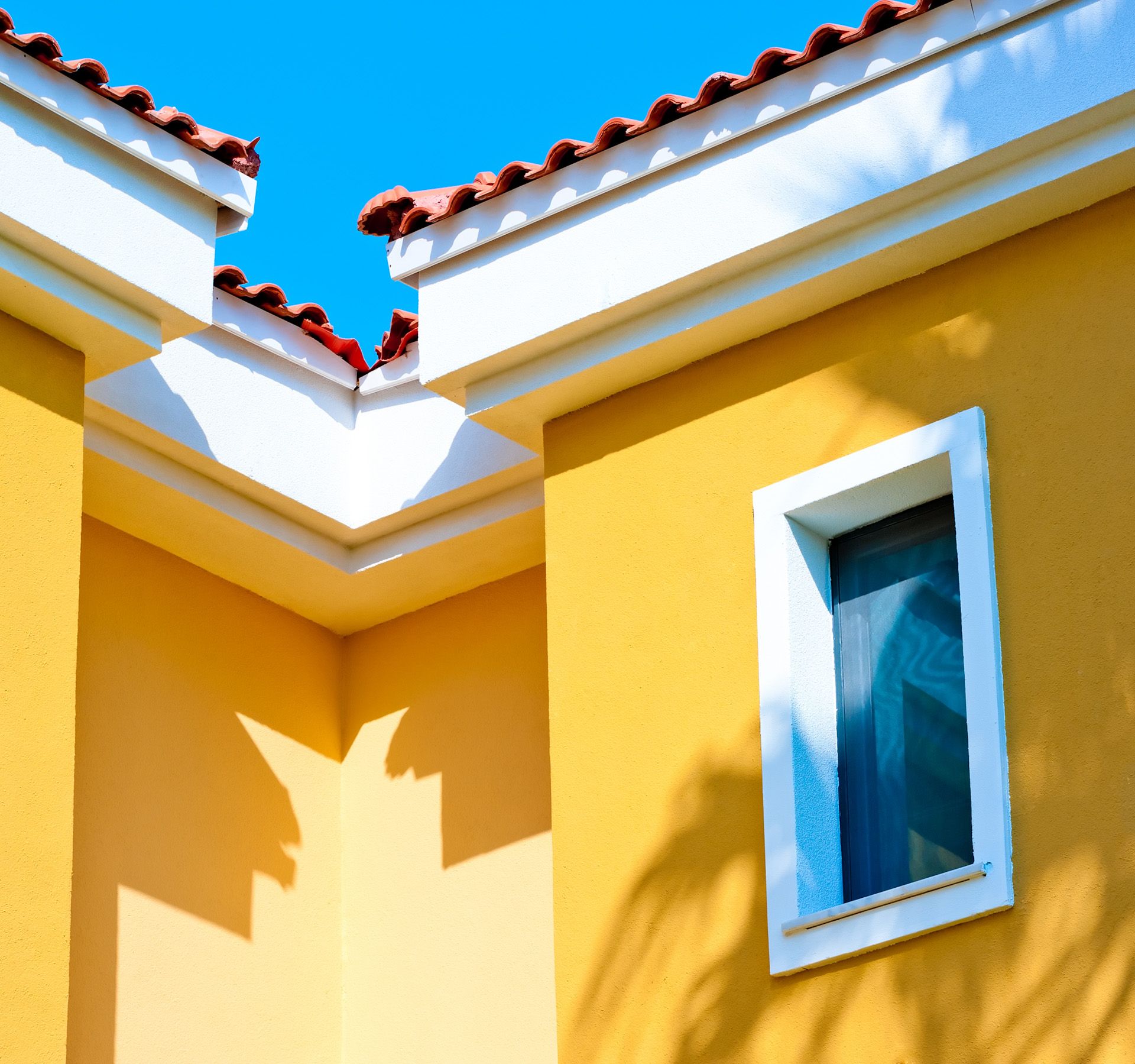 A yellow building with a white trim and a window