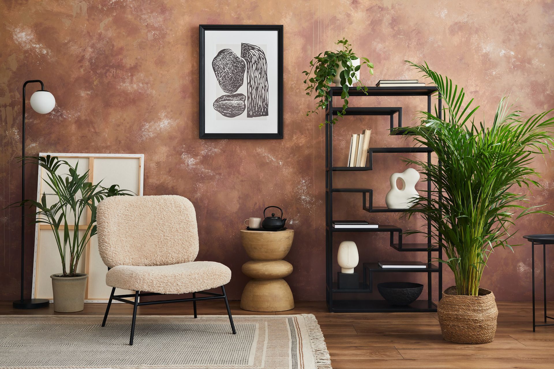 A living room with a chair, plants, a shelf and a picture on the wall.