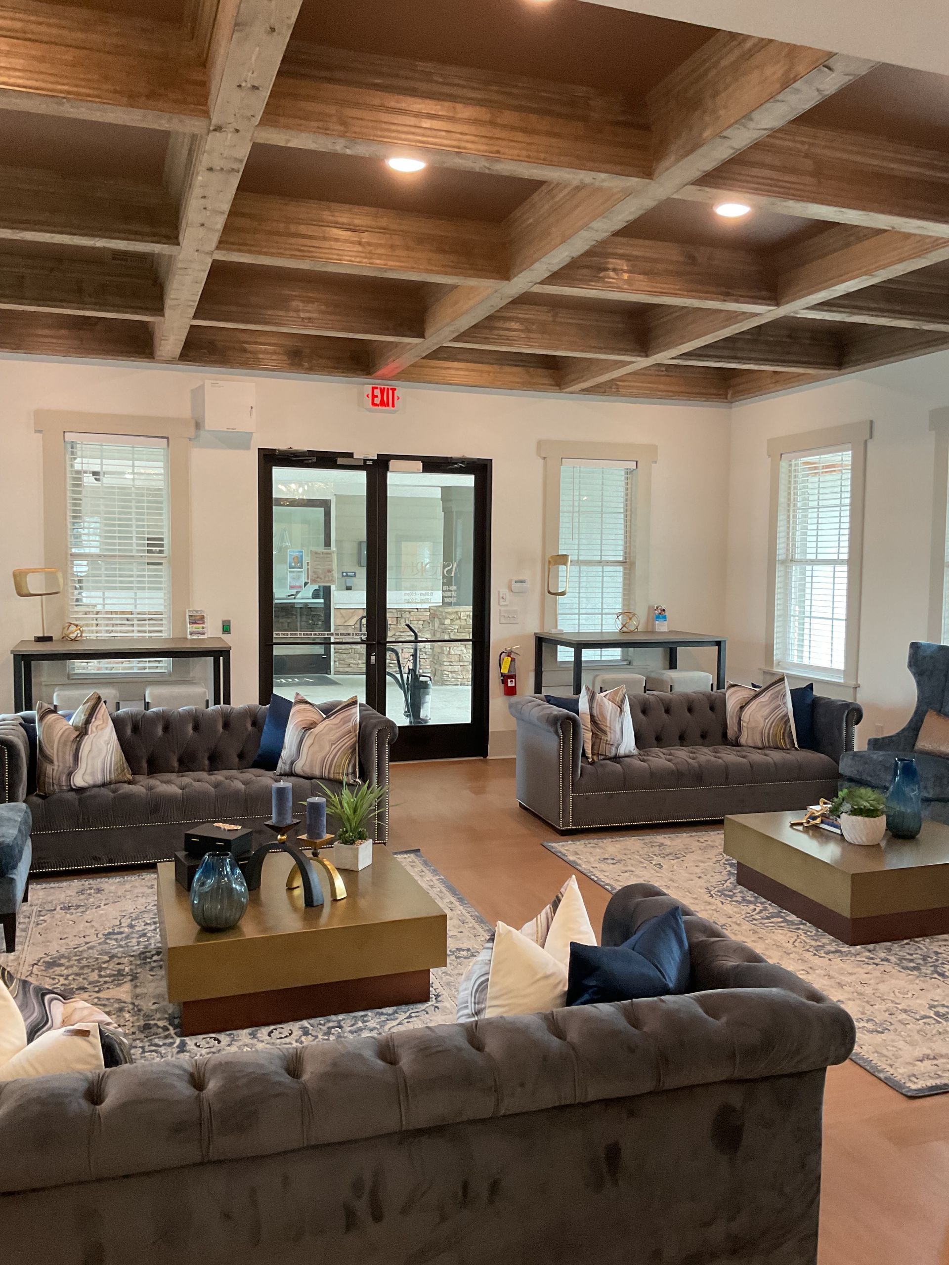 Cozy lounge with tufted sofas, wooden ceiling beams, and large windows.
