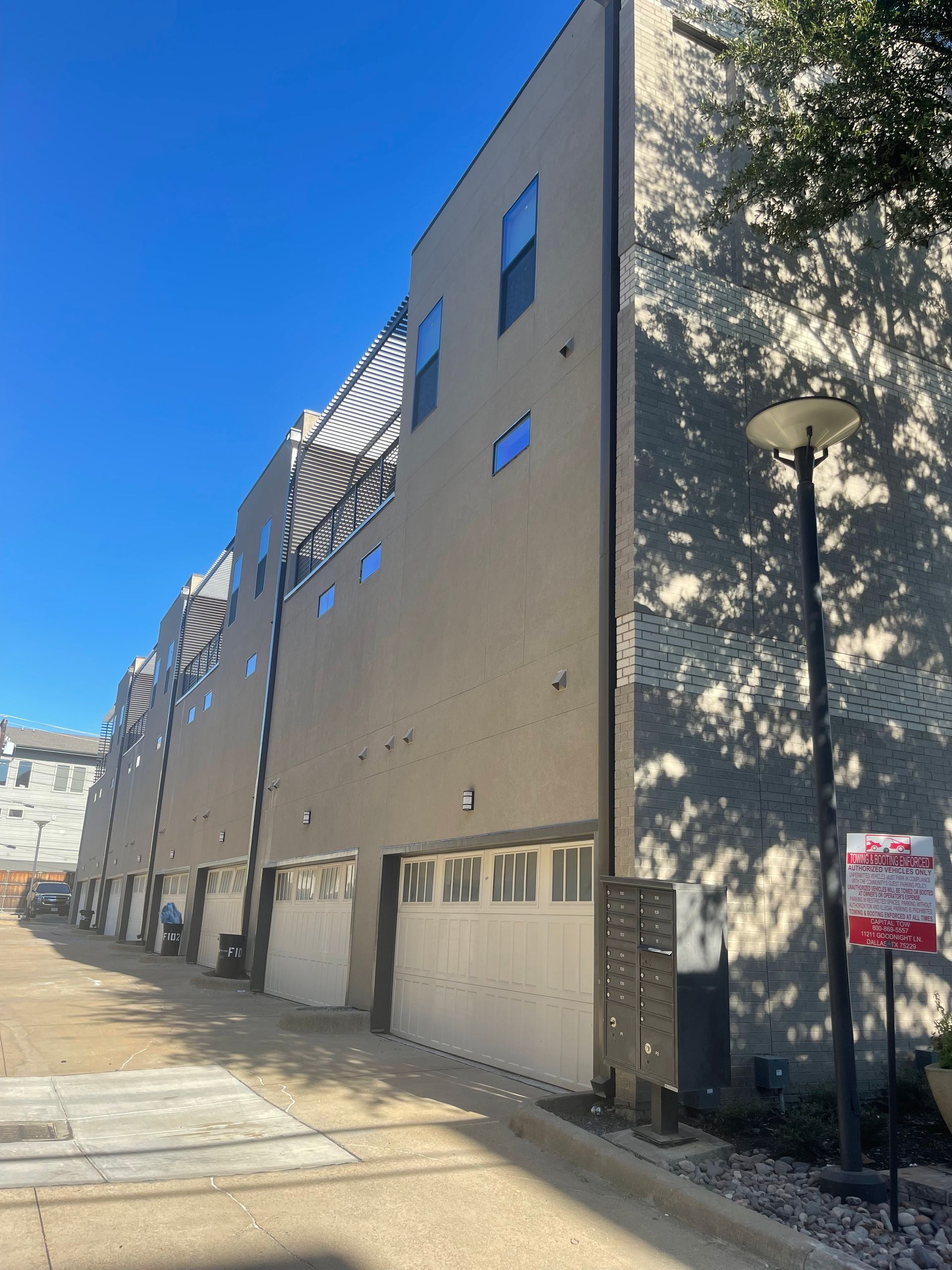 Row of modern townhouses with garages and windows against a blue sky.