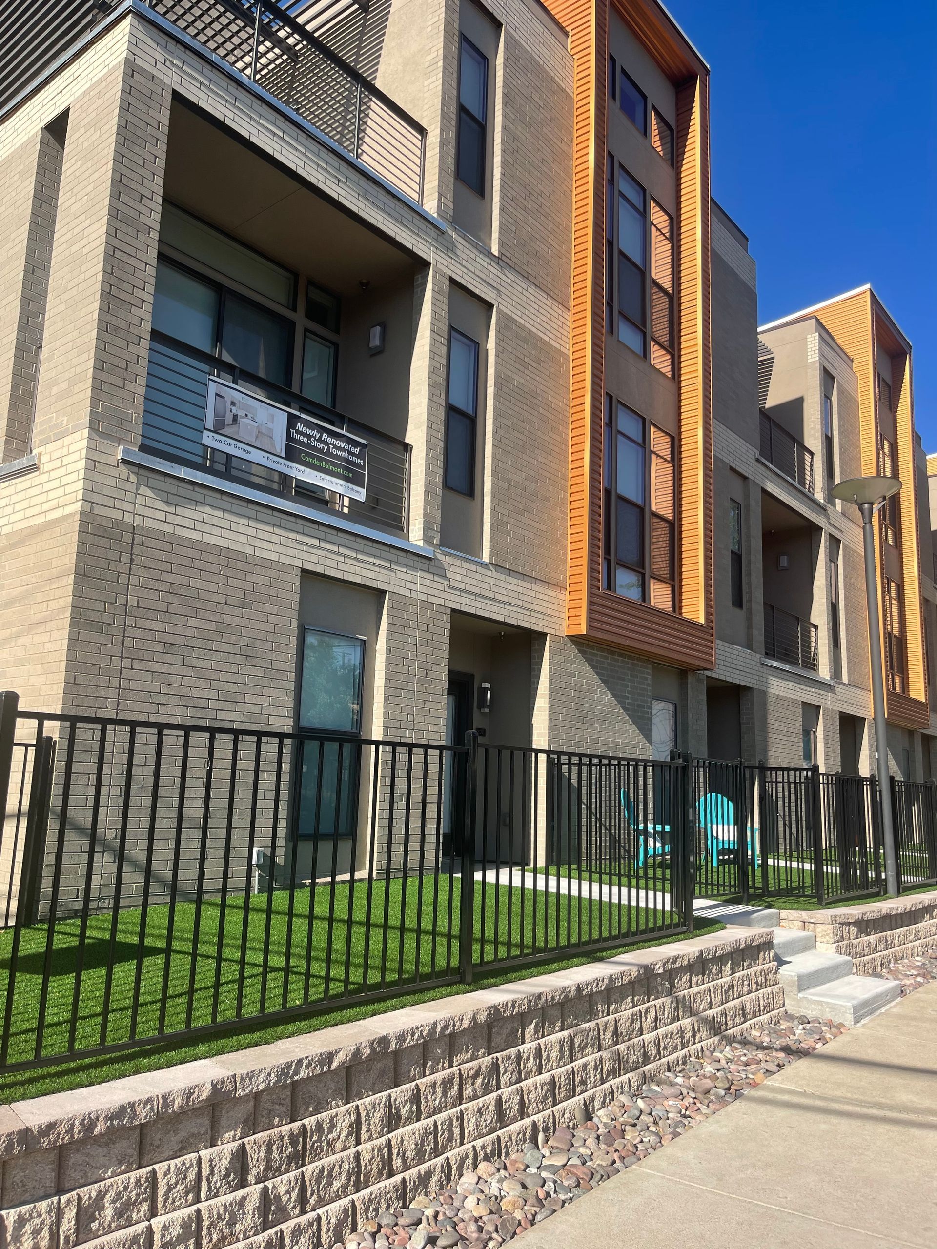 Multi-story brick building with balconies and a black fence.