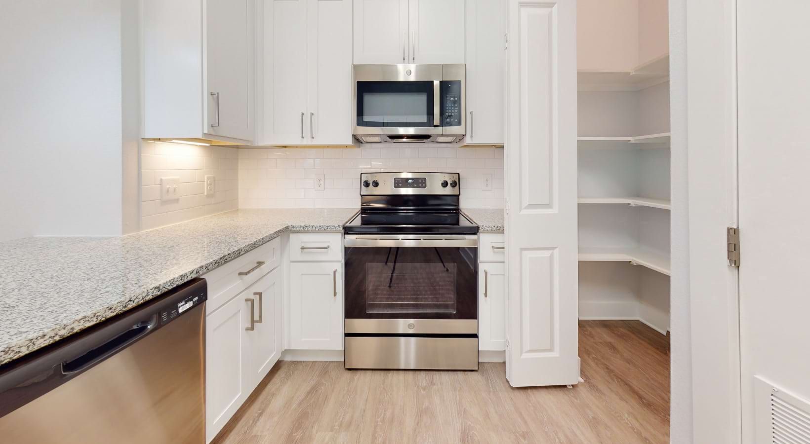 White kitchen with stainless steel appliances, granite countertops, and pantry.
