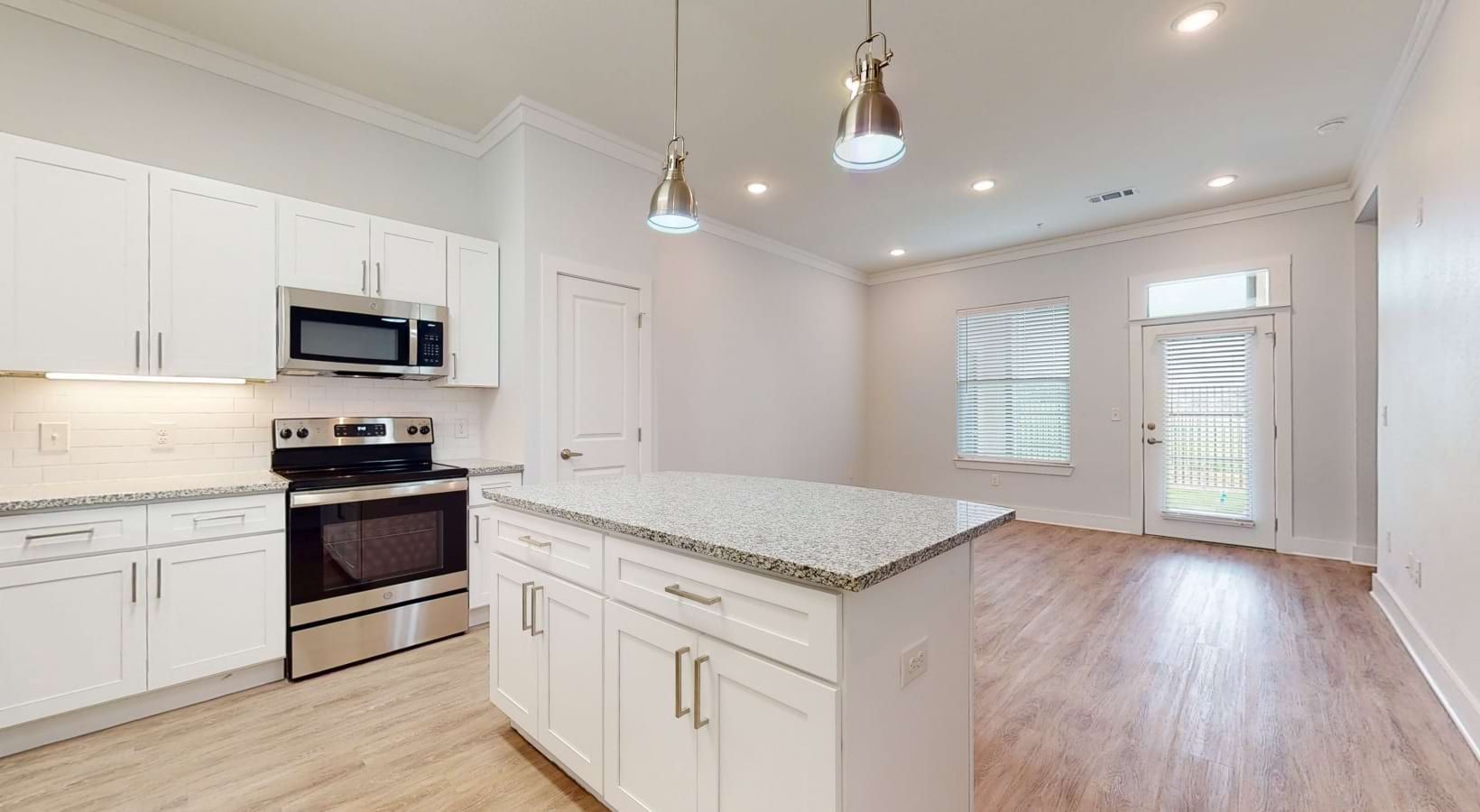 White kitchen with island, stainless steel appliances, and wood flooring.