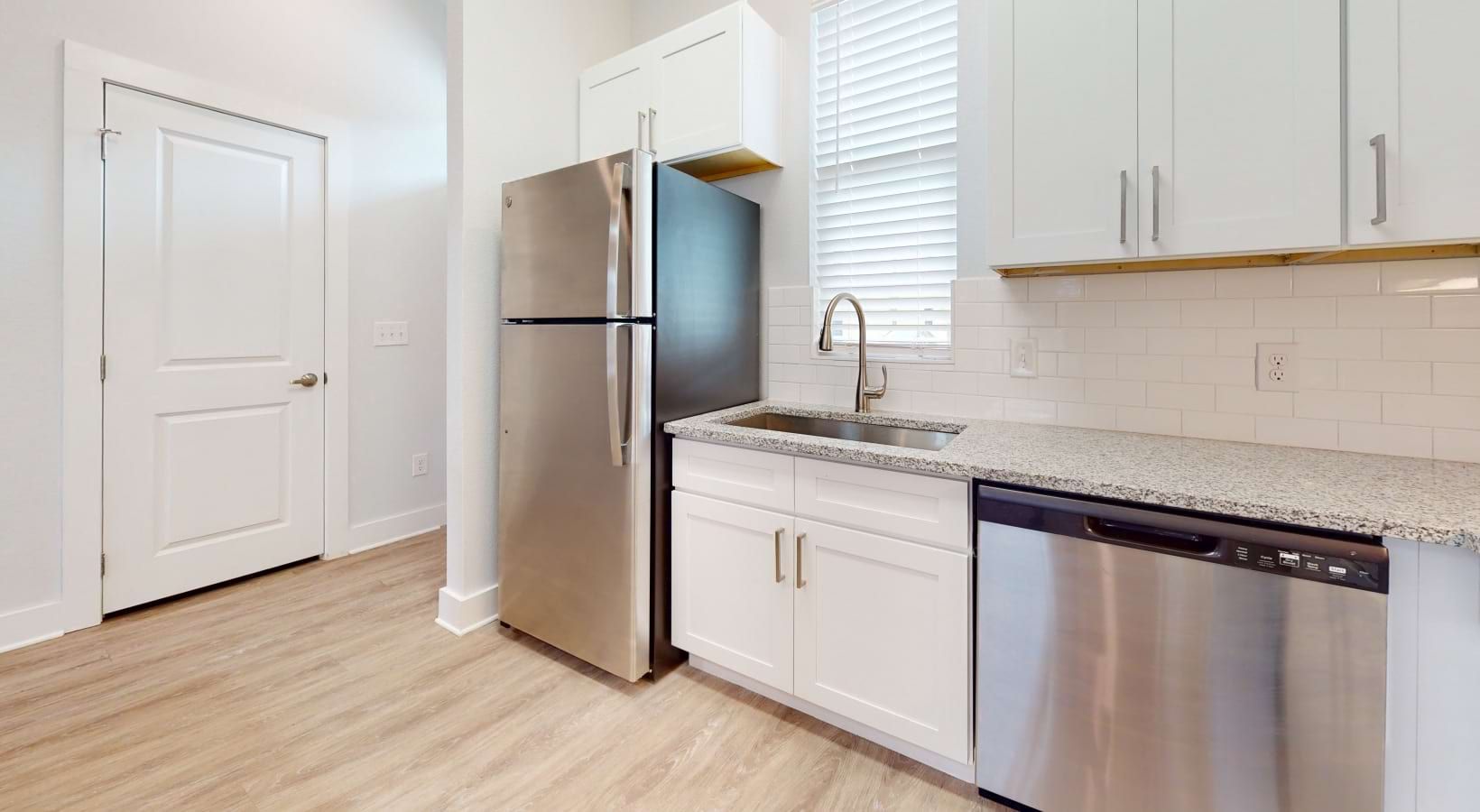 Kitchen with white cabinets, stainless steel appliances, and wood-look flooring.