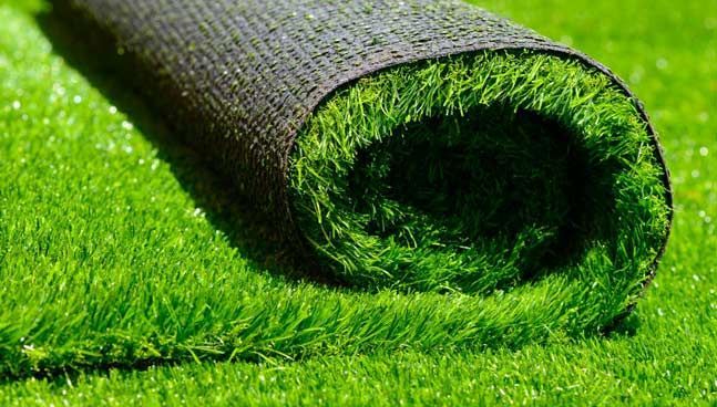 Roll of lush artificial grass being unrolled on a balcony
