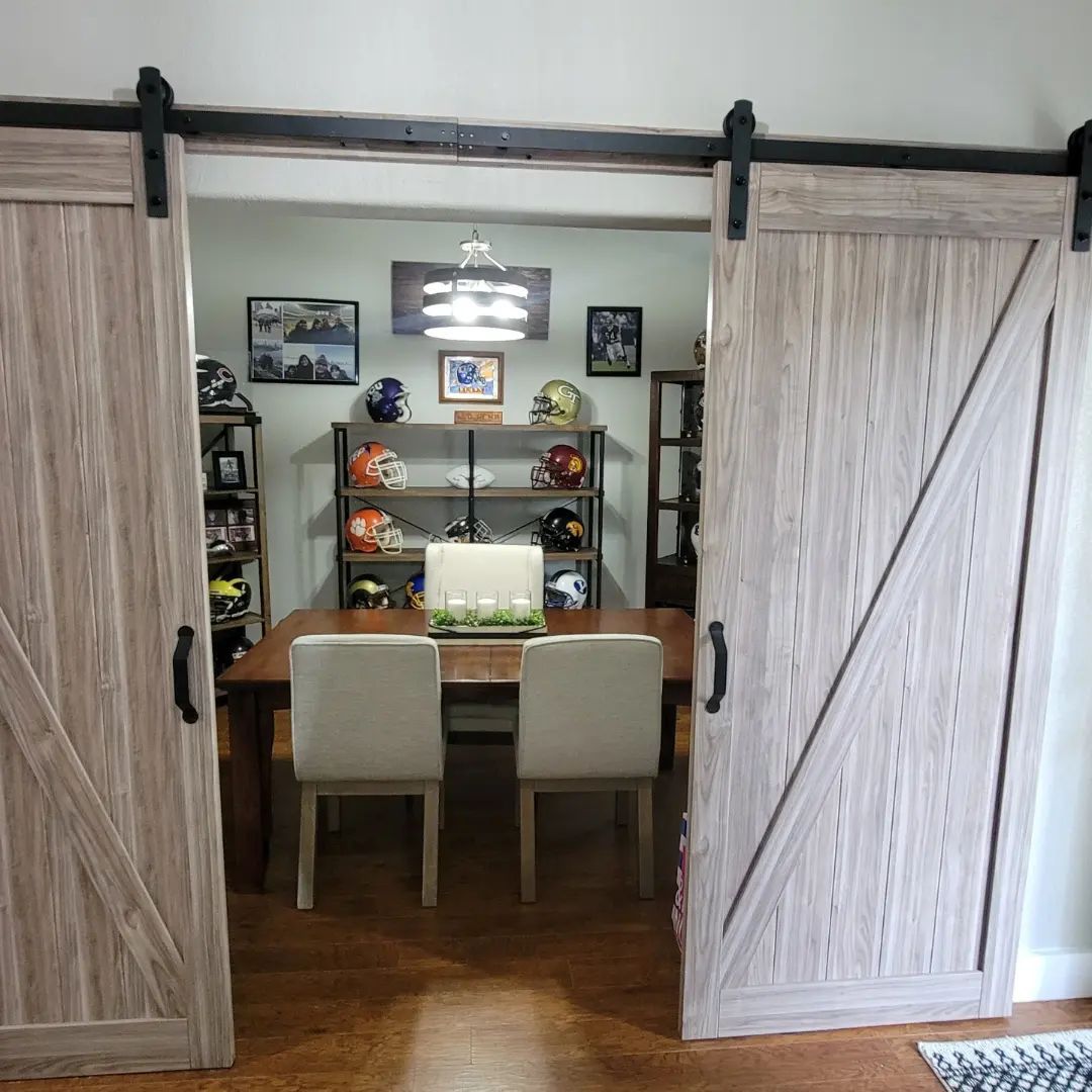 Barn doors open to a dining room with a table, chairs, and sports memorabilia.