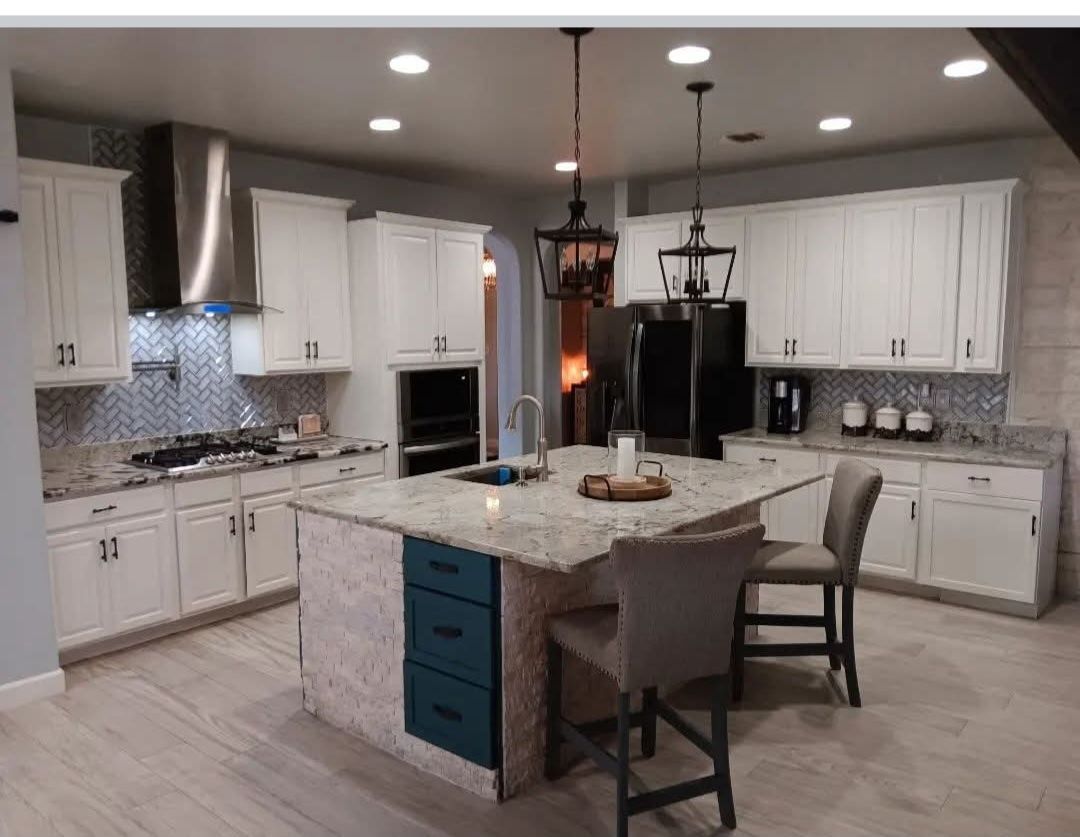 Modern kitchen with white cabinets, island with blue drawers, granite counters, and stainless steel appliances.