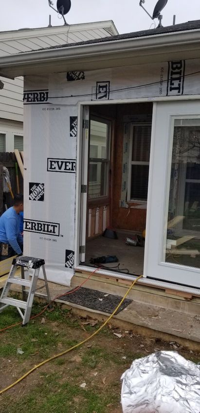 Construction of a house with exposed framing, an open door, and a person working outside.