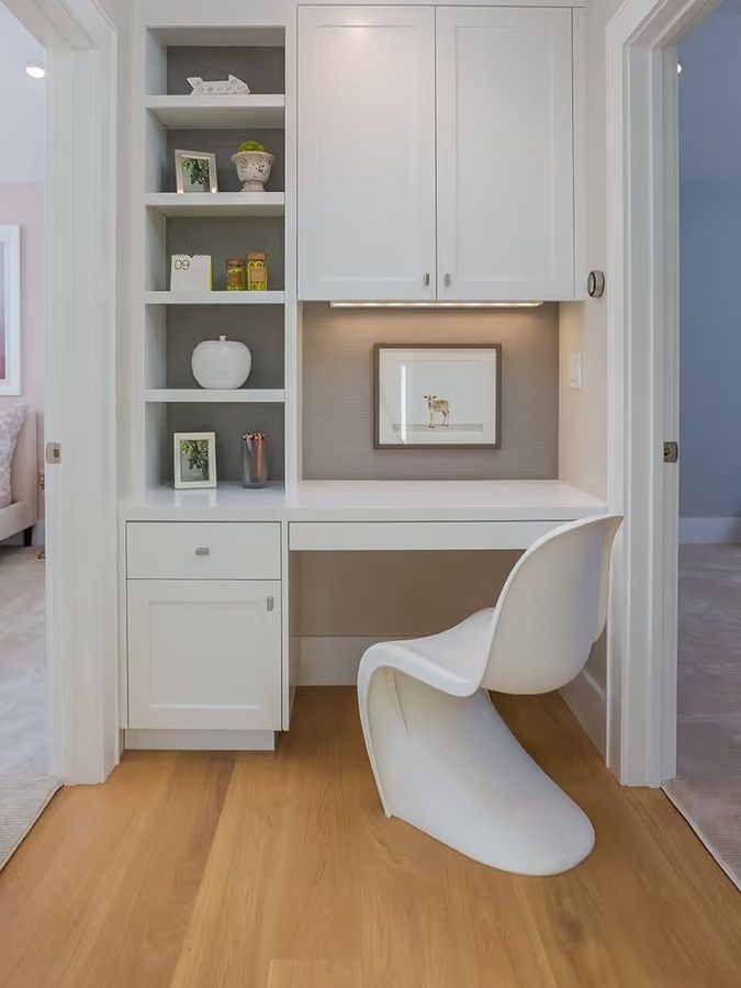 A white chair is sitting in front of a desk in a room.