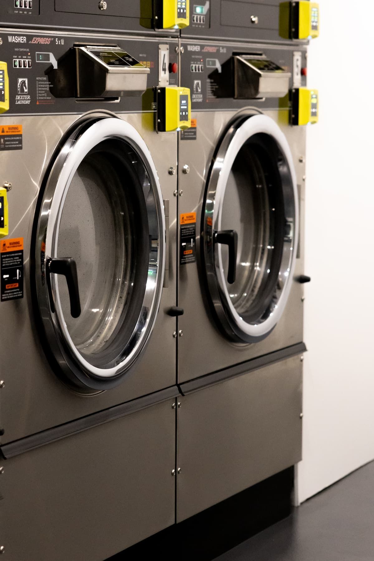 Two Washing Machines Are Stacked On Top Of Each Other In A Laundromat — Tanilba Bay Laundromat In Tanilba Bay, NSW