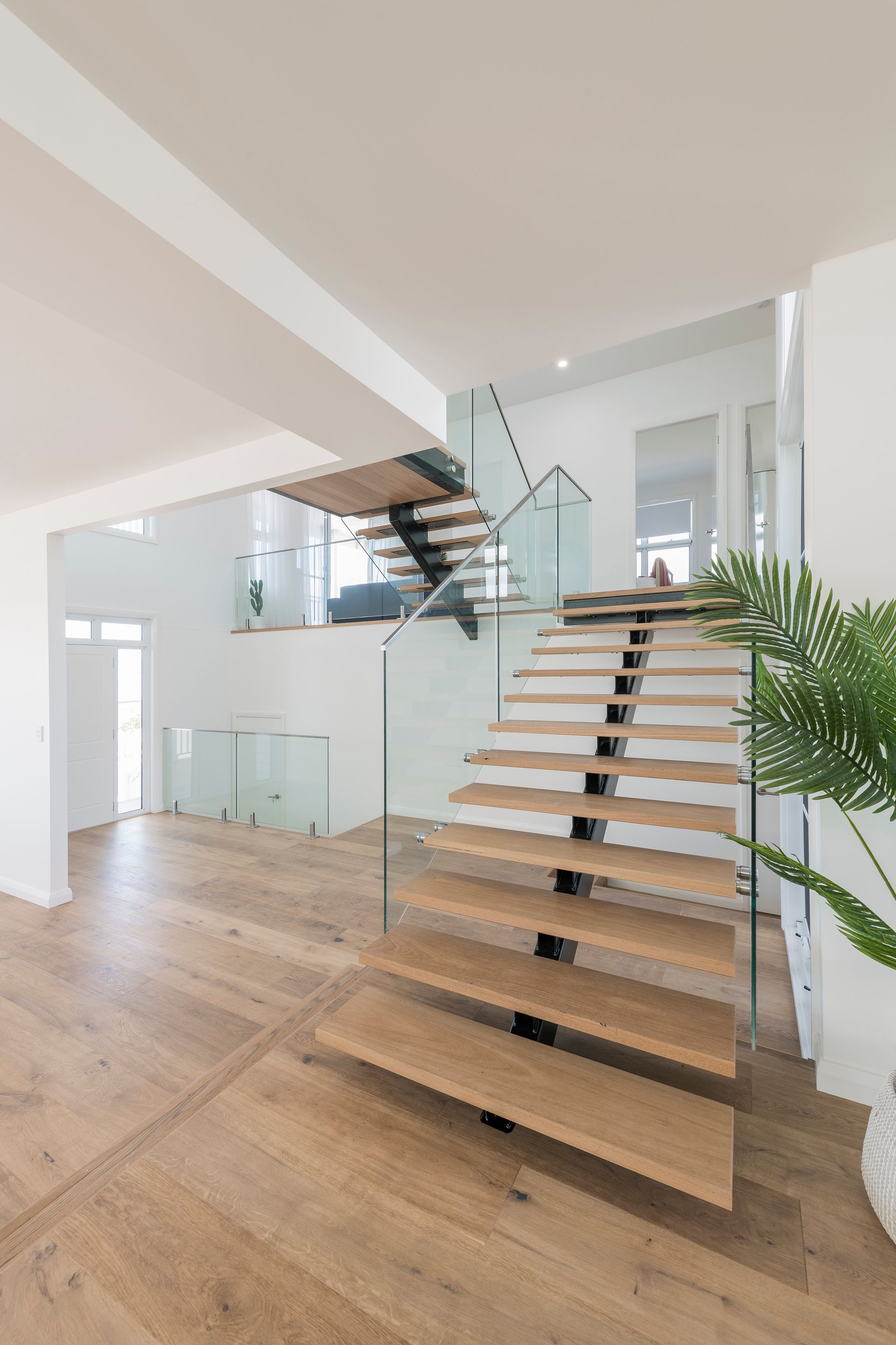 a Modern Wooden Staircase With Glass Railings in a Bright, and White Interior — Indie Living In Lake Macquarie, NSW