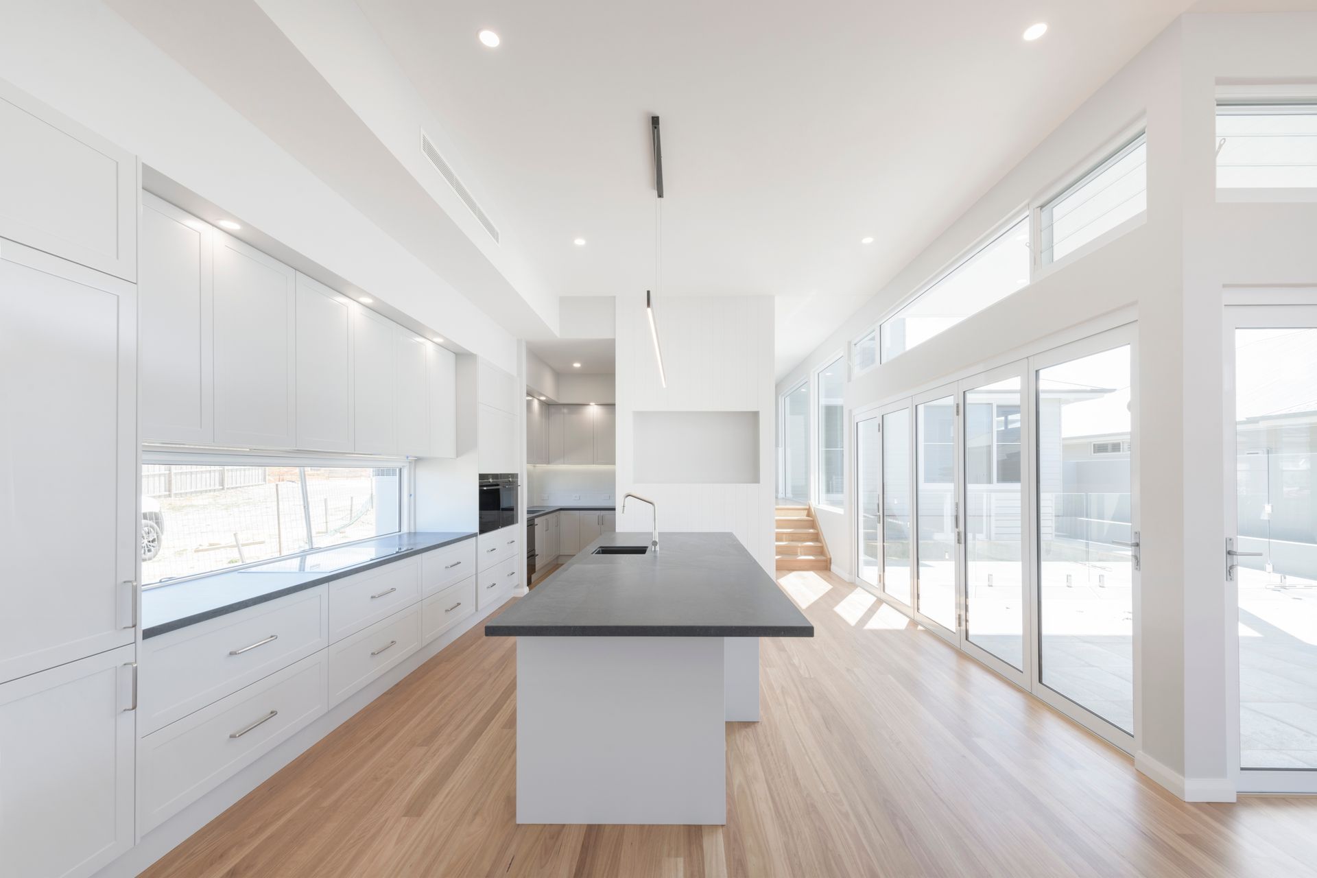 Bright White Modern Kitchen With Dark Island, Wooden Floor, and Large Windows — Indie Living In Lake Macquarie, NSW