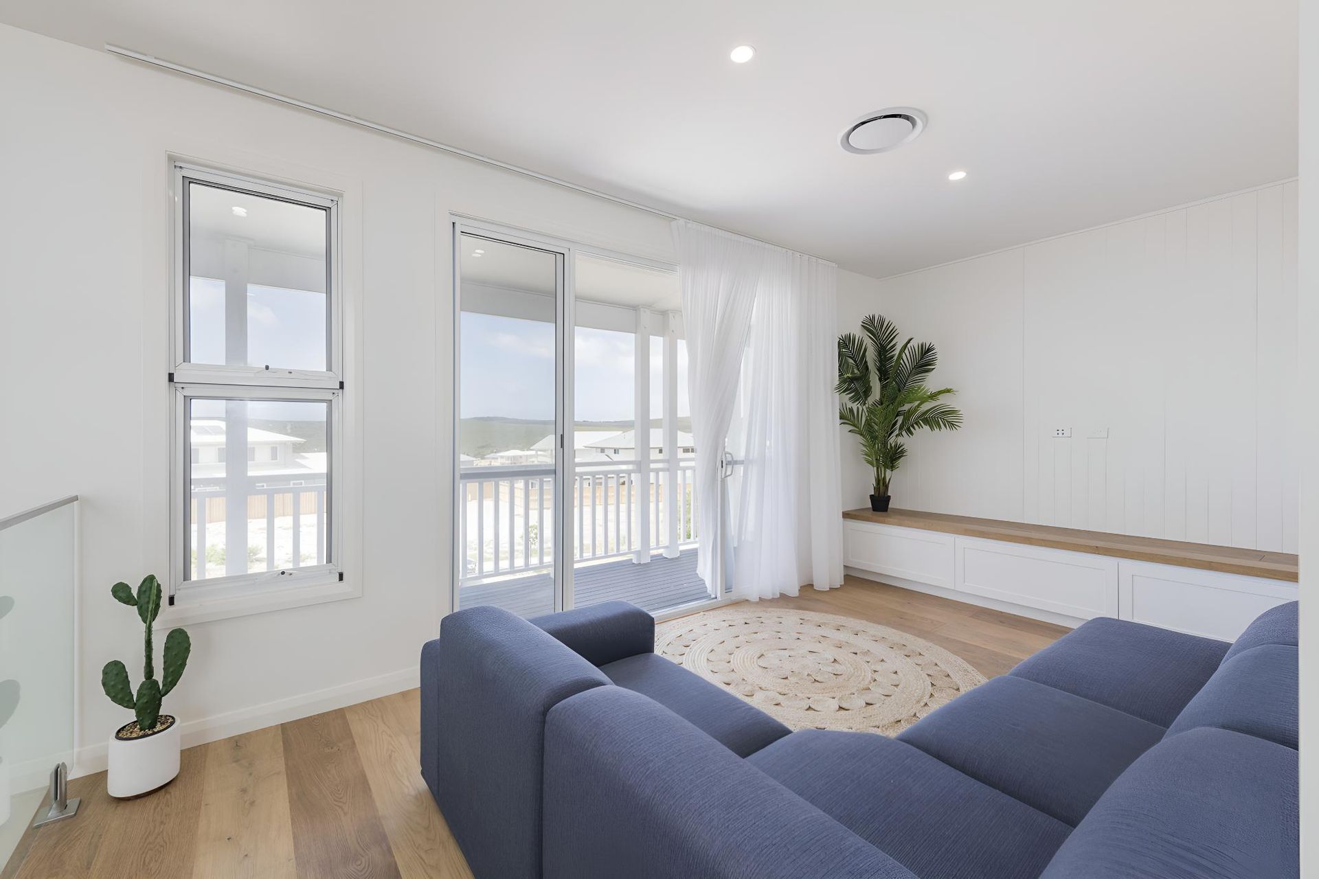 A Living Room With a Blue Couch and a Balcony — Indie Living In Bennetts Green, NSW