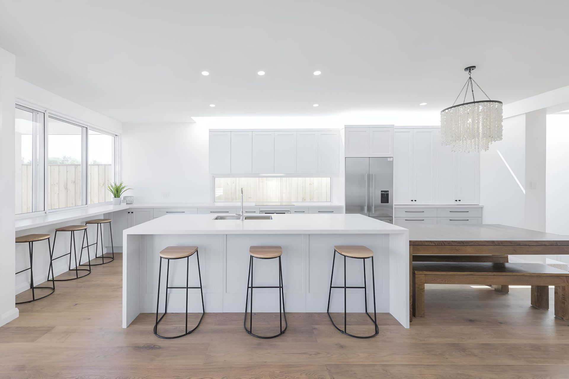A Kitchen With White Cabinets , Stools , a Table and a Refrigerator — Indie Living In Bennetts Green, NSW