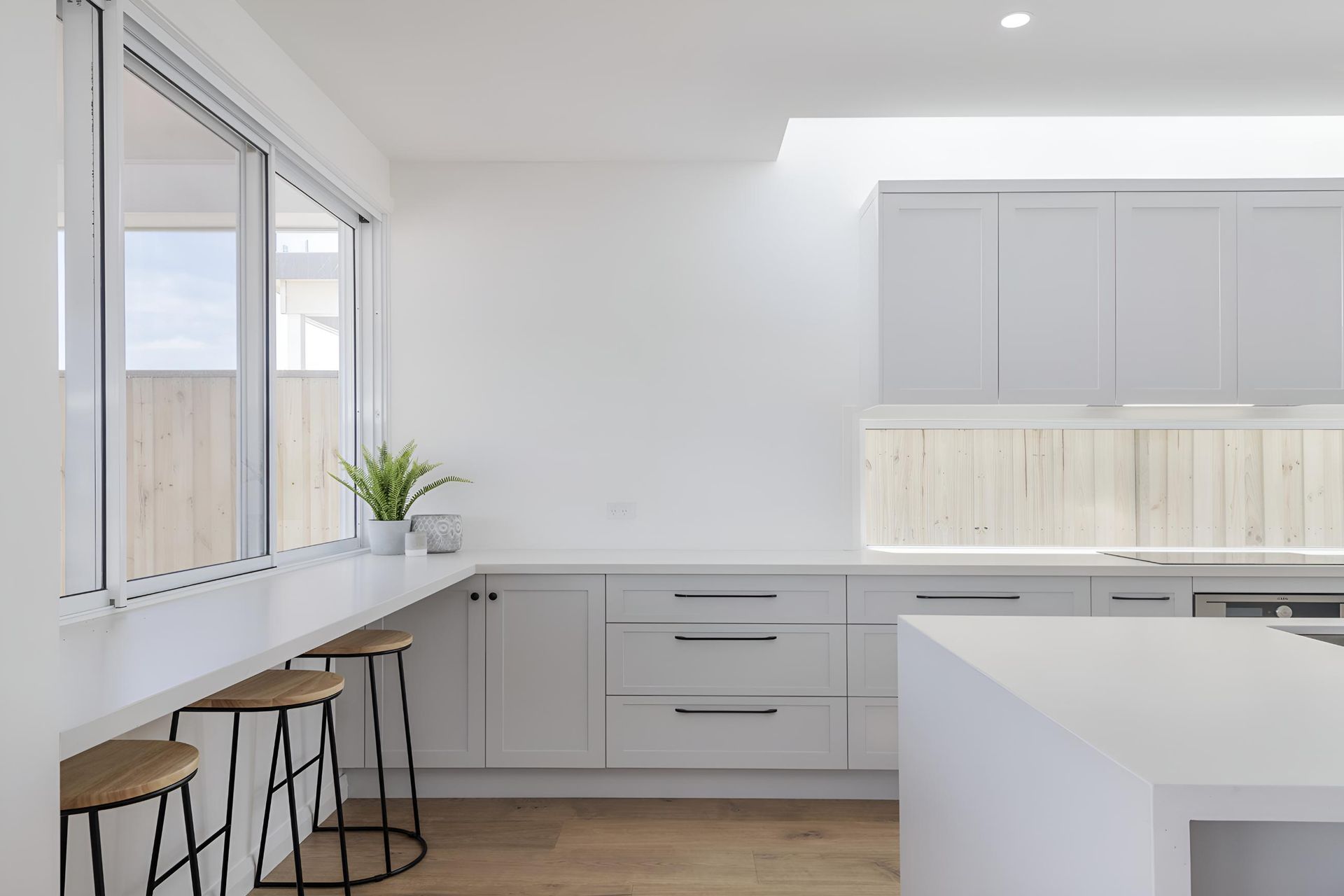 A Kitchen With White Cabinets and Stools and a Large Window — Indie Living In Bennetts Green, NSW