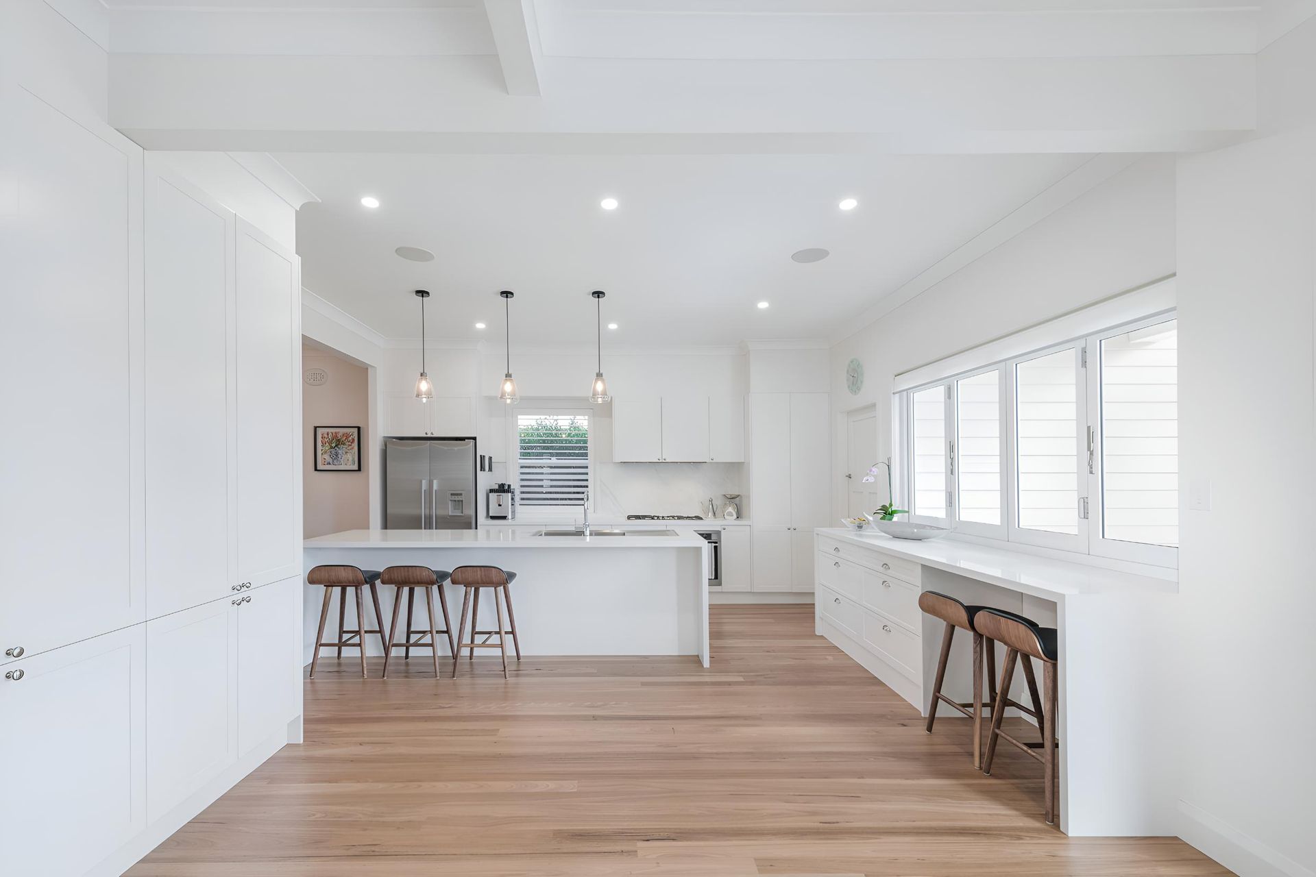 A Kitchen With White Cabinets and Wooden Floors and Stools — Indie Living In Bennetts Green, NSW