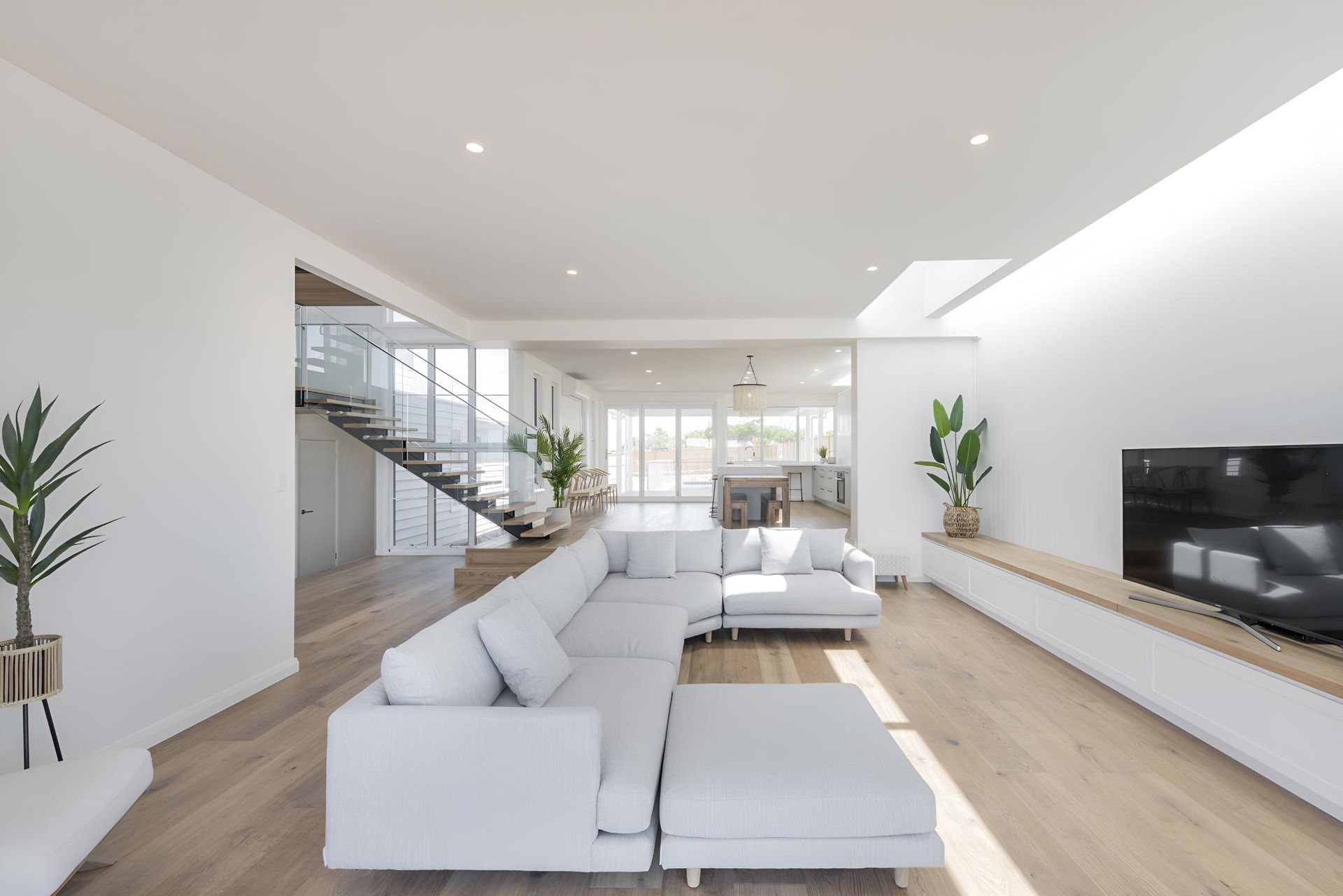 A Living Room With a Large White Sectional Couch and a Flat Screen Tv — Indie Living In Bennetts Green, NSW