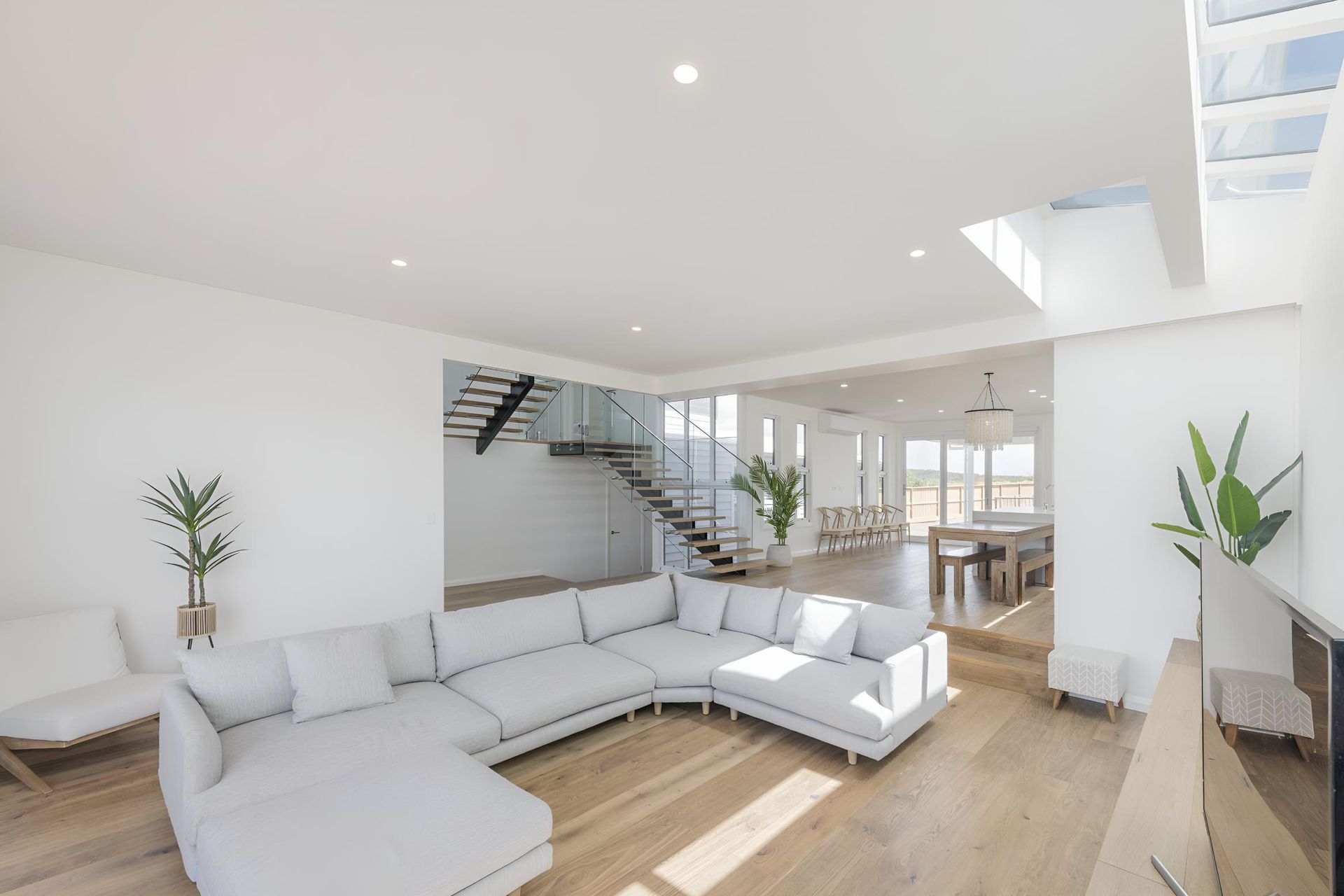 A Living Room With a Large Sectional Couch and Stairs — Indie Living In Bennetts Green, NSW
