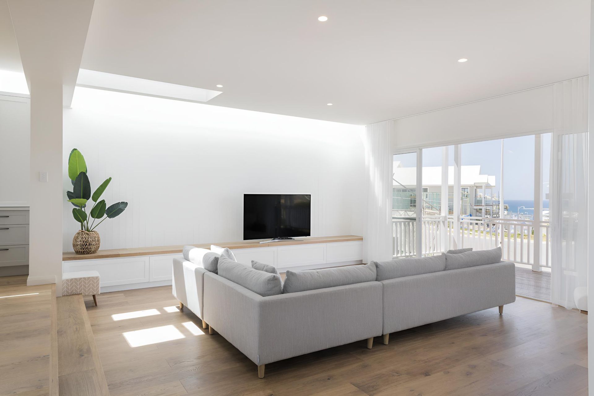 A Living Room With a Large Sectional Couch and a Flat Screen Tv — Indie Living In Bennetts Green, NSW