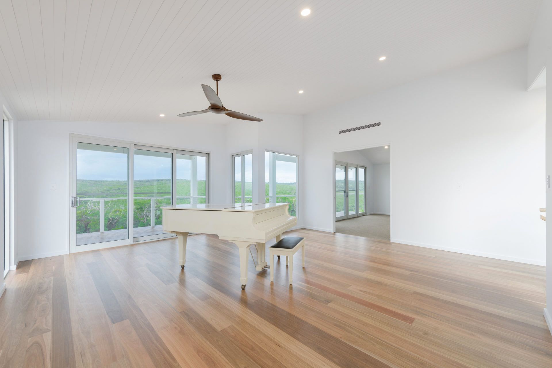 An Empty Living Room With a White Piano and a Ceiling Fan — Indie Living In Bennetts Green, NSW