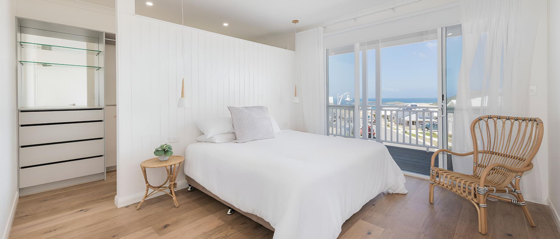 A Bedroom With a Bed , Chair and Sliding Glass Doors With a View of the Ocean — Indie Living In Bennetts Green, NSW