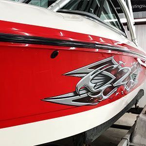 A red and white boat is parked on a trailer after paint correction service