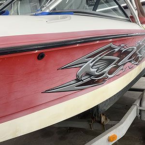 A red and white boat is parked on a trailer.