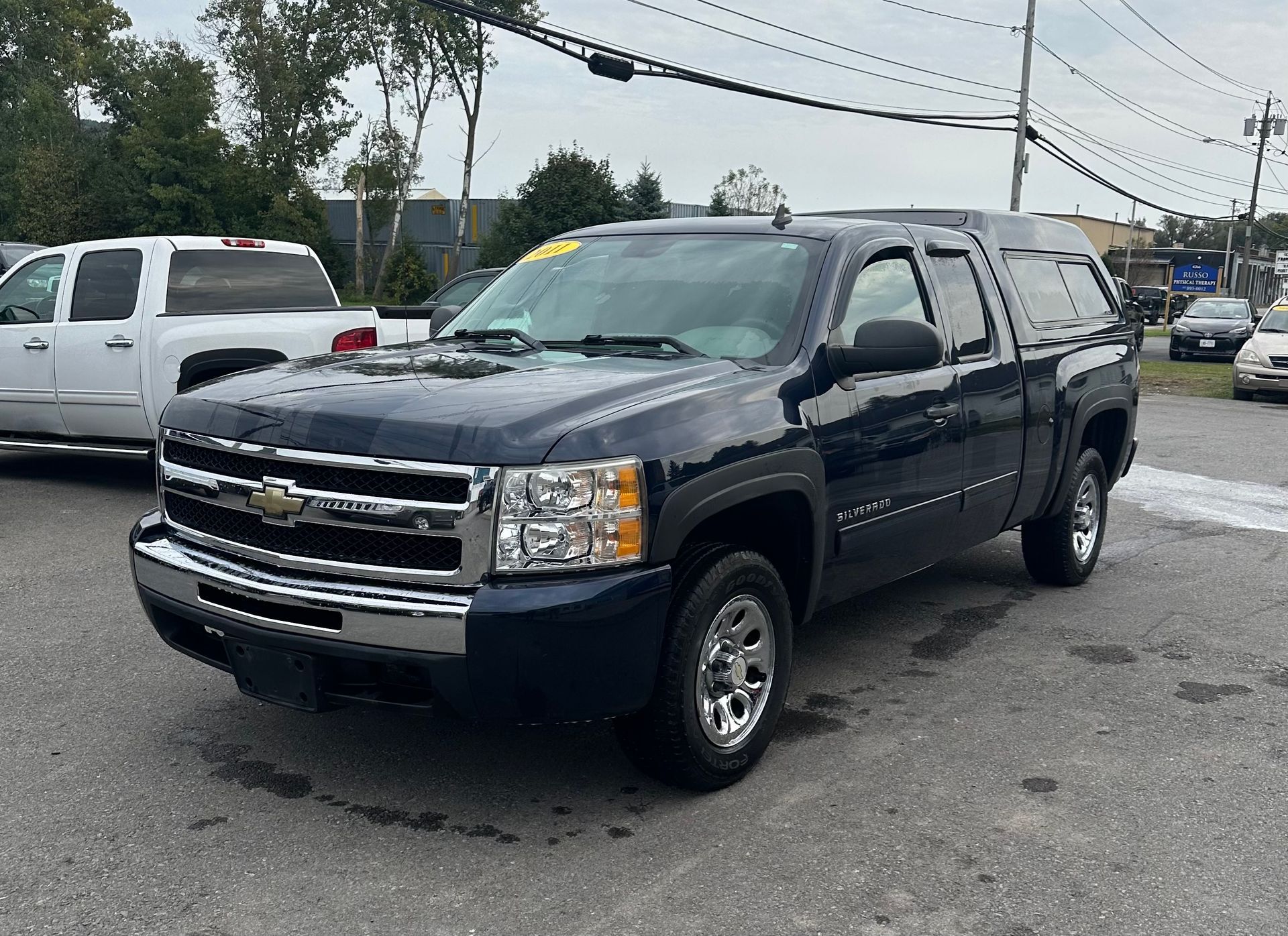 A blue chevrolet silverado pickup truck is parked in a parking lot.