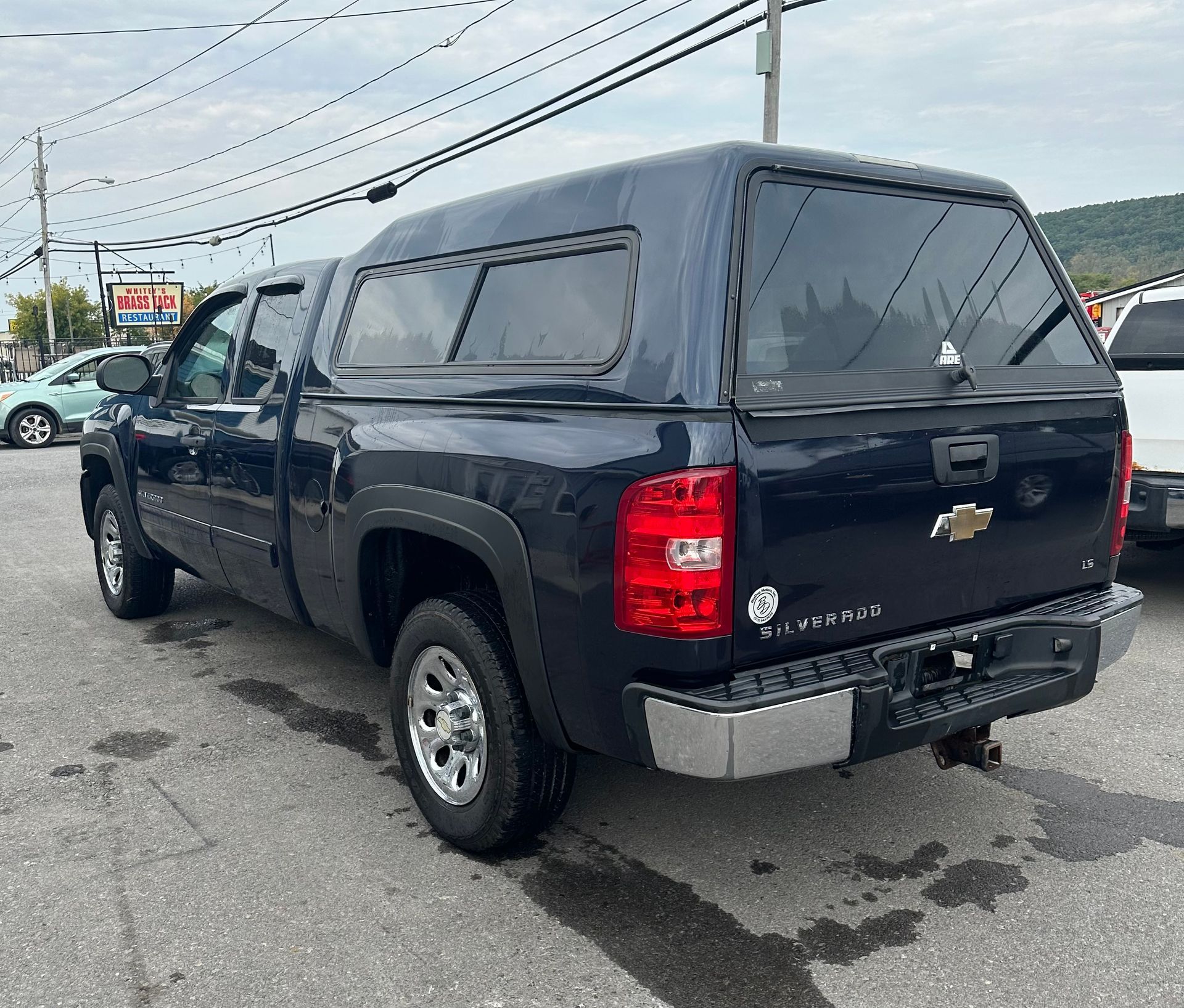 A black truck with a canopy is parked in a parking lot.