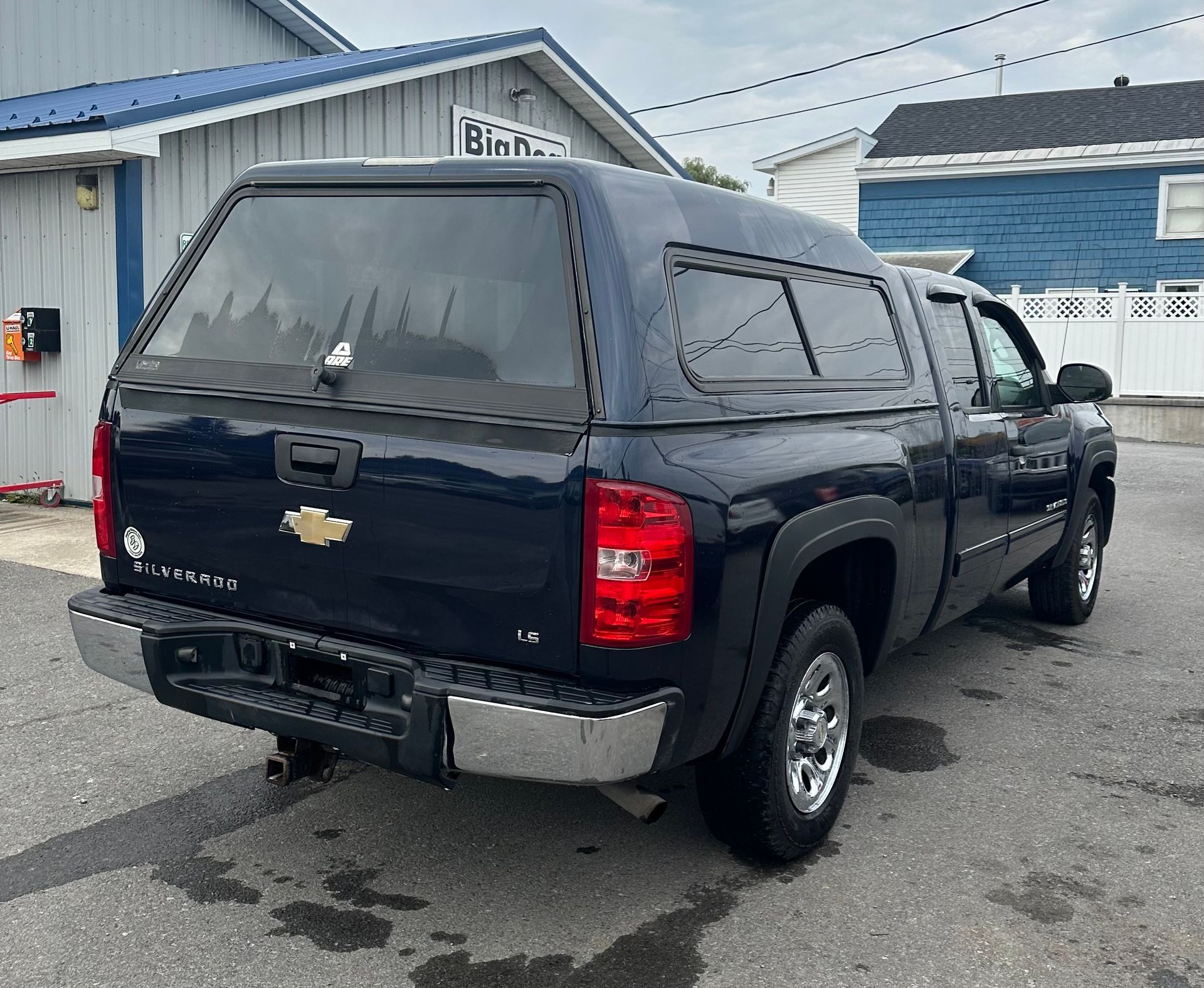 A black truck with a canopy on top of it is parked in front of a building.