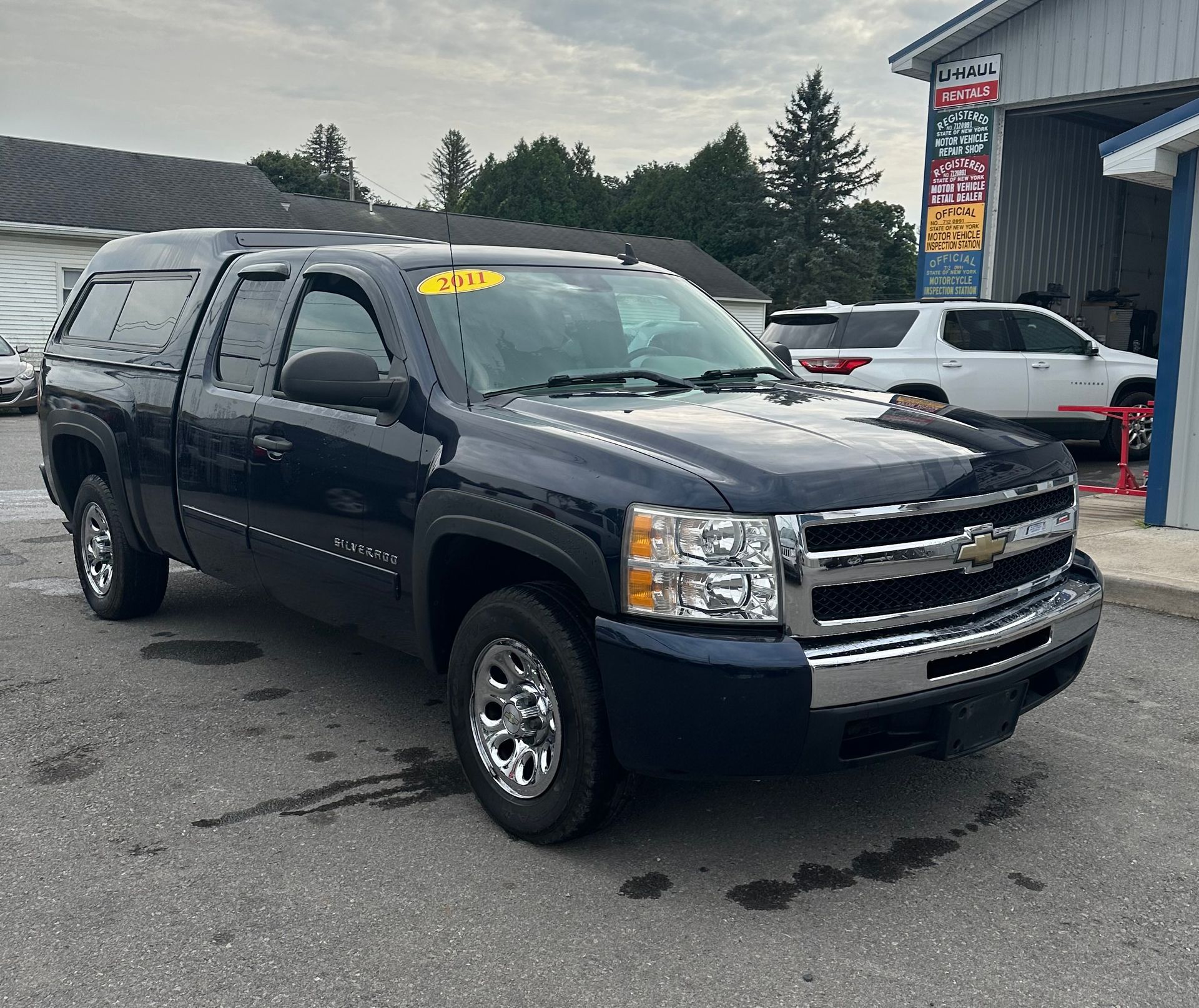 A blue chevrolet silverado truck is parked in front of a building.