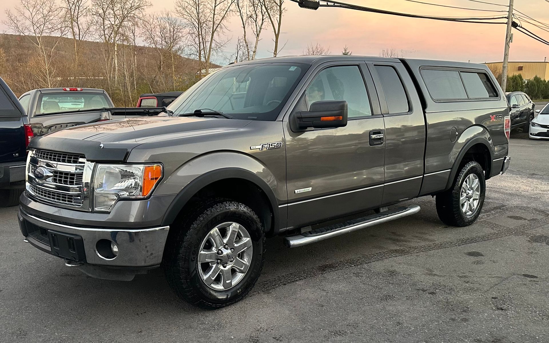 A gray ford f150 truck is parked in a parking lot.