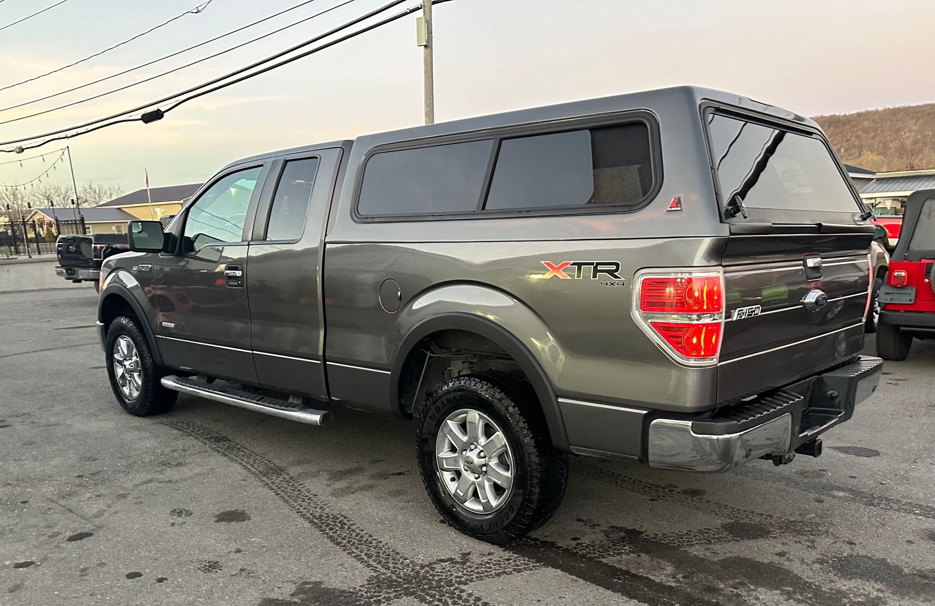 A gray truck with a canopy on top of it is parked in a parking lot.