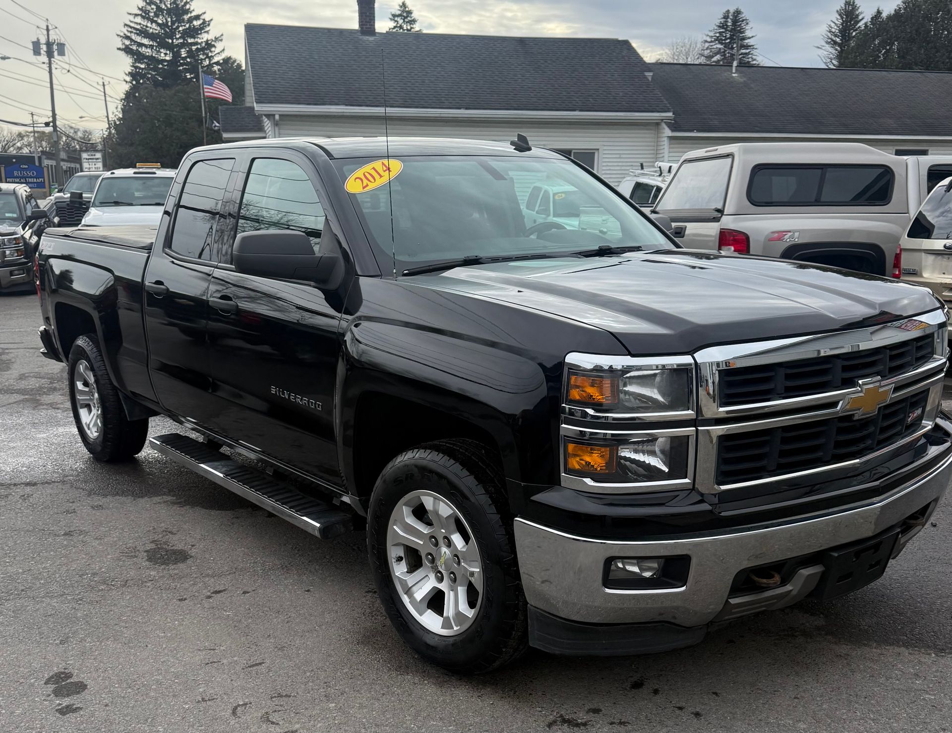 Black Chevrolet Silverado truck, parked outdoors, with a yellow price tag.