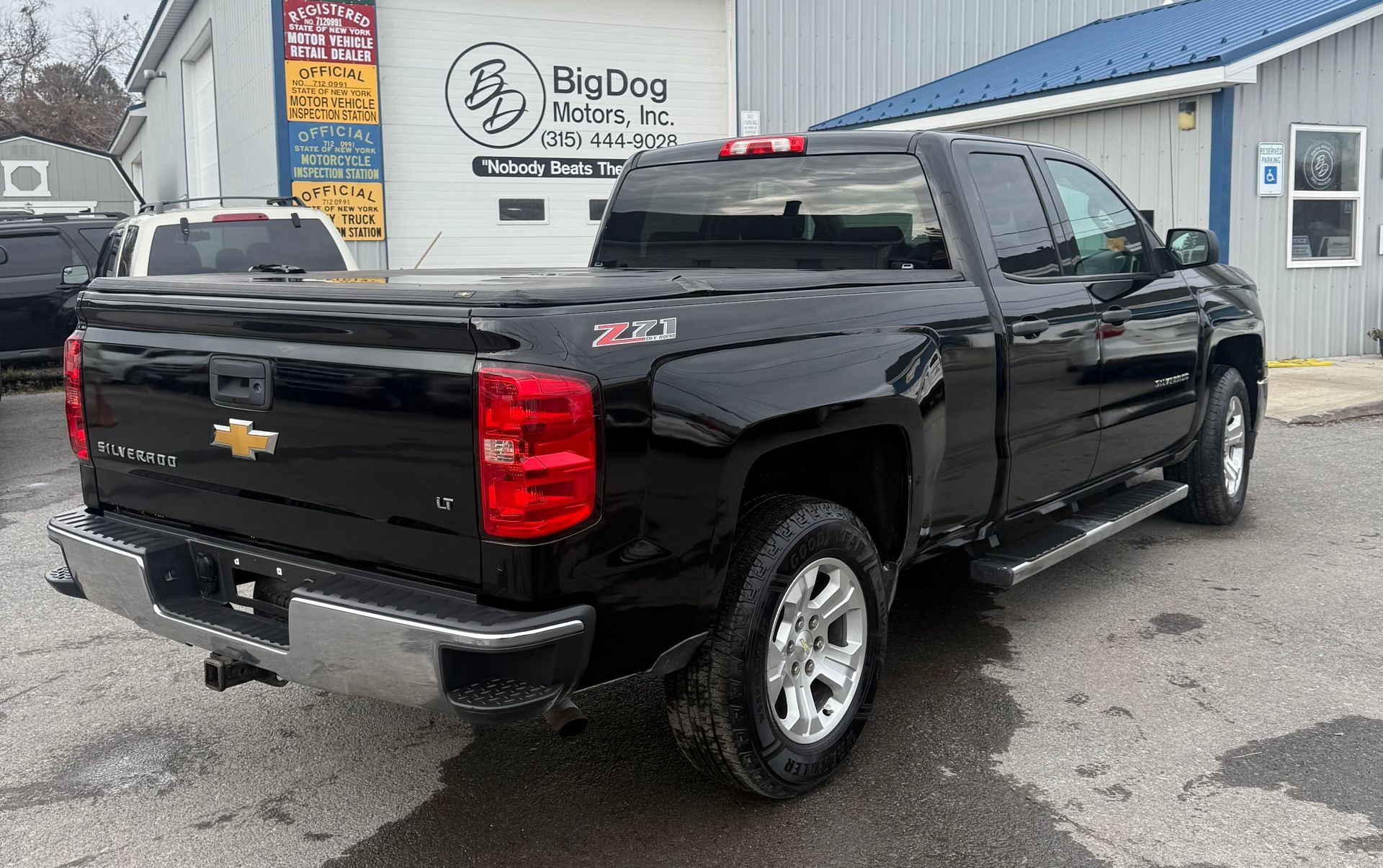Black Chevrolet Silverado pickup truck parked outside a business with 