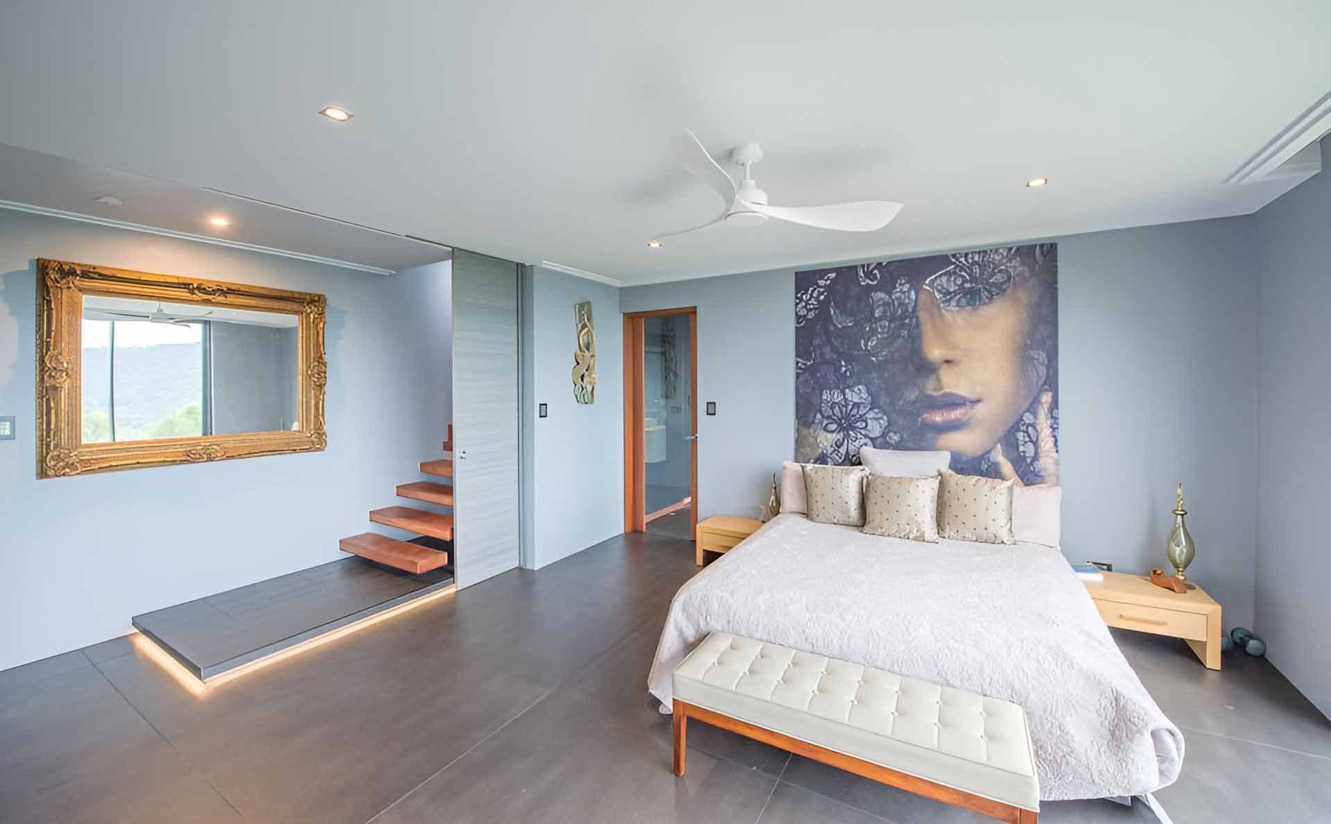 A Bedroom With A Large Bed And A Painting On The Wall — Omni Builders In Bungalow, QLD