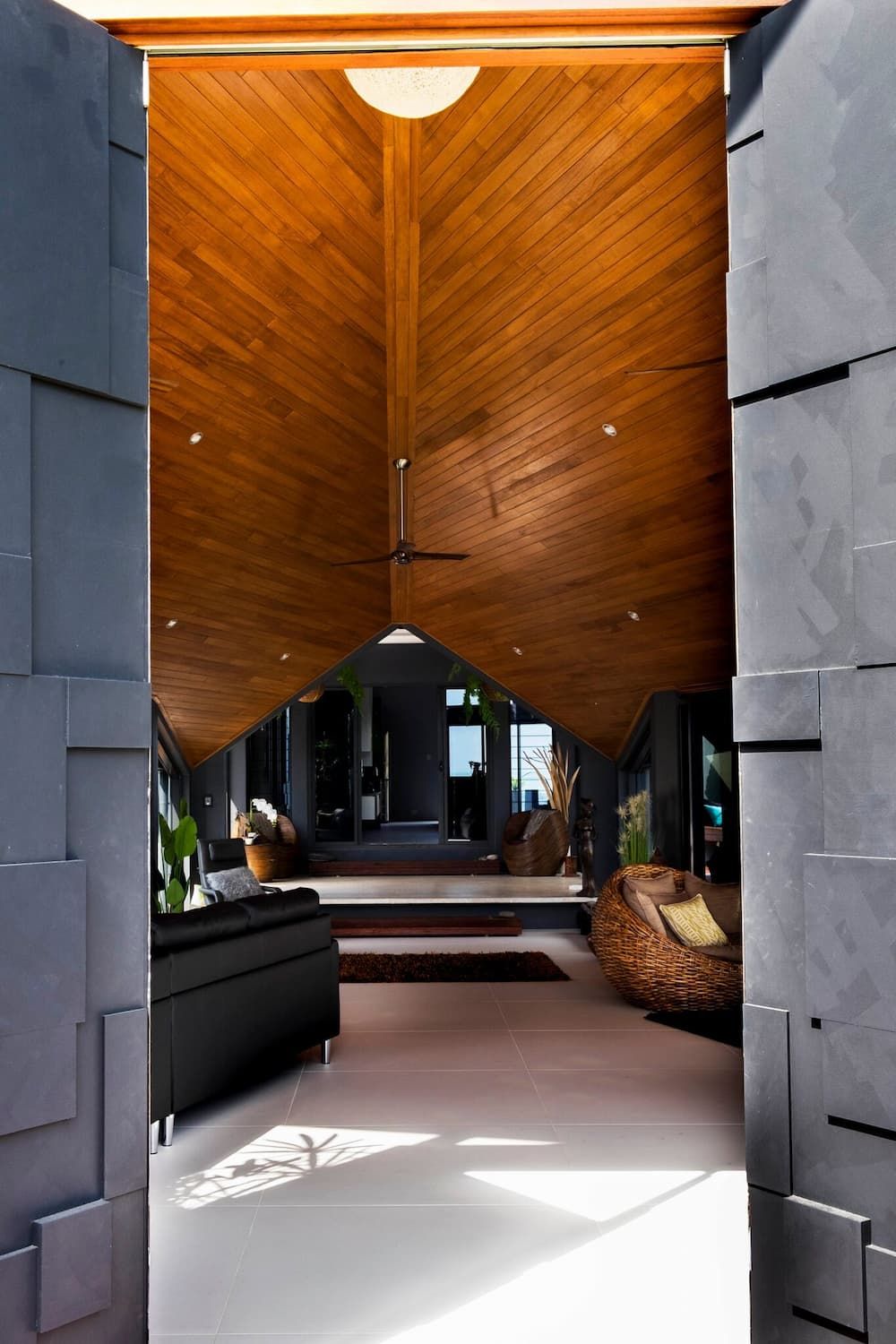 A Living Room With A Wooden Ceiling And A Black Couch — Omni Builders In Gordonvale, QLD