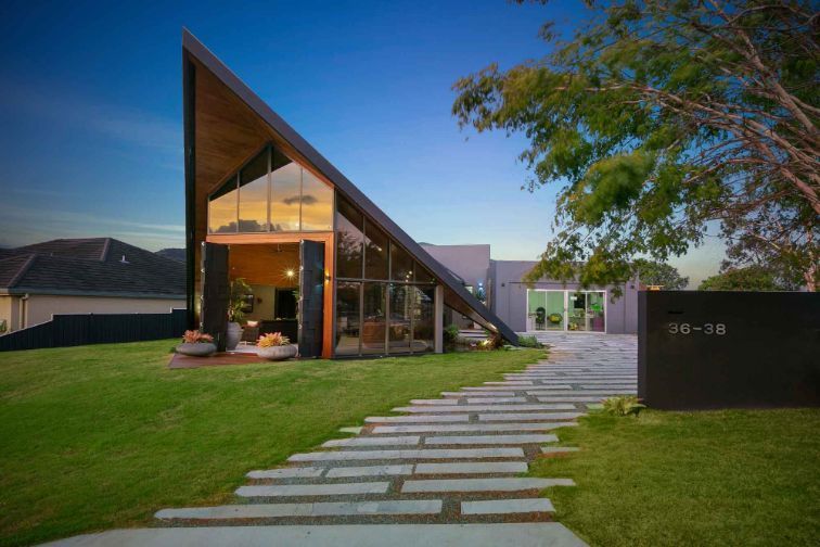 A Modern House With a Triangle Shaped Roof and a Walkway Leading to It — Omni Builders In Bungalow, QLD