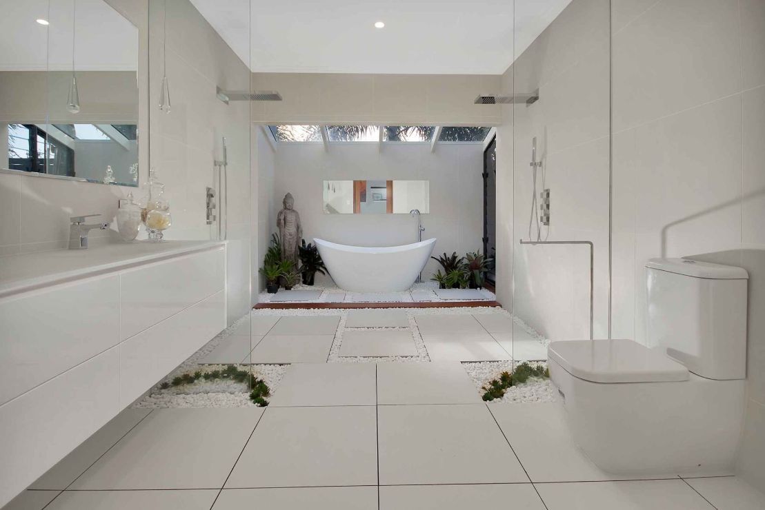 A Bathroom With a Bathtub , Toilet , Sink and Mirror — Omni Builders In Bungalow, QLD