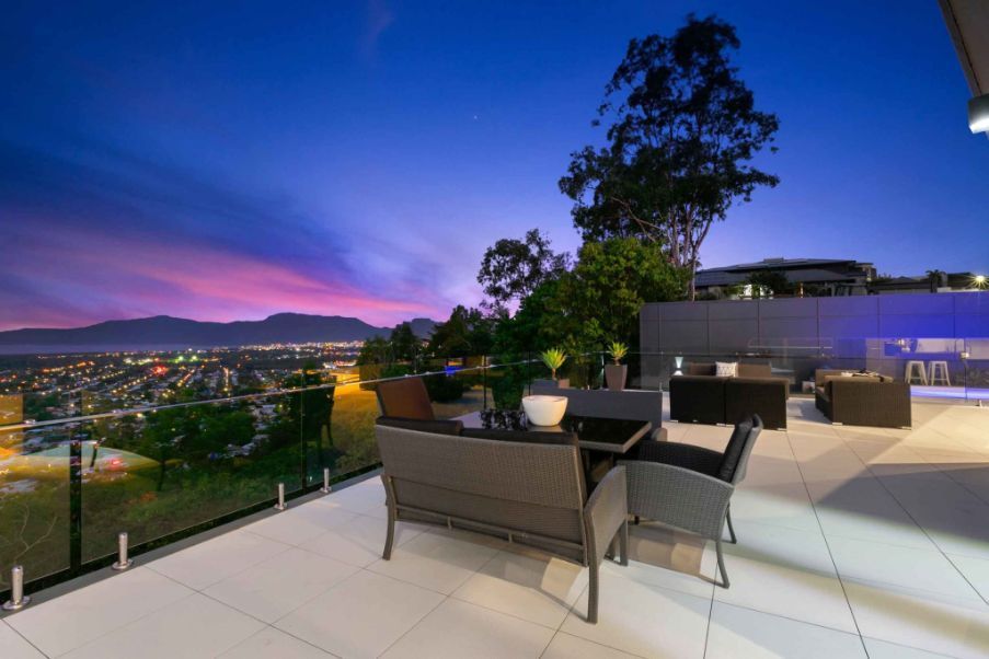 A Patio With a Table and Chairs and a View of a City at Night — Omni Builders In Bungalow, QLD