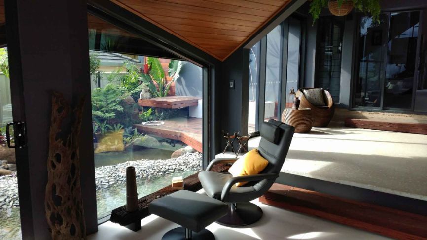 A Living Room With a Chair and Ottoman and a Large Window — Omni Builders In Bungalow, QLD