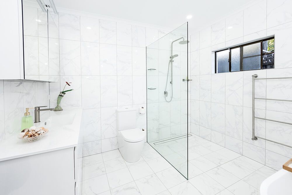A Bathroom With a Walk in Shower , Toilet , Sink and Mirror — Omni Builders In Bungalow, QLD